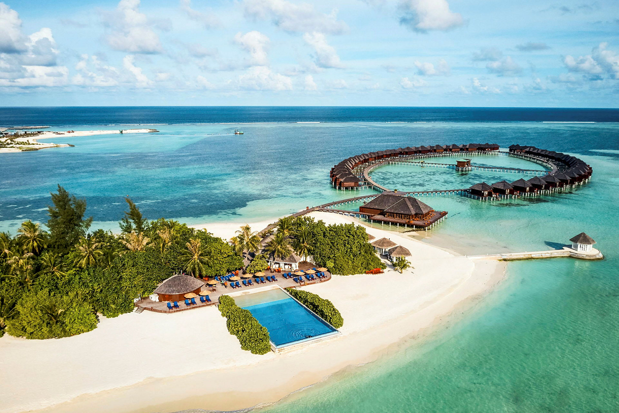 Luftvy av en tropisk kust med sandstrand, hav och övervattensbungalower. (AI-genererad text)