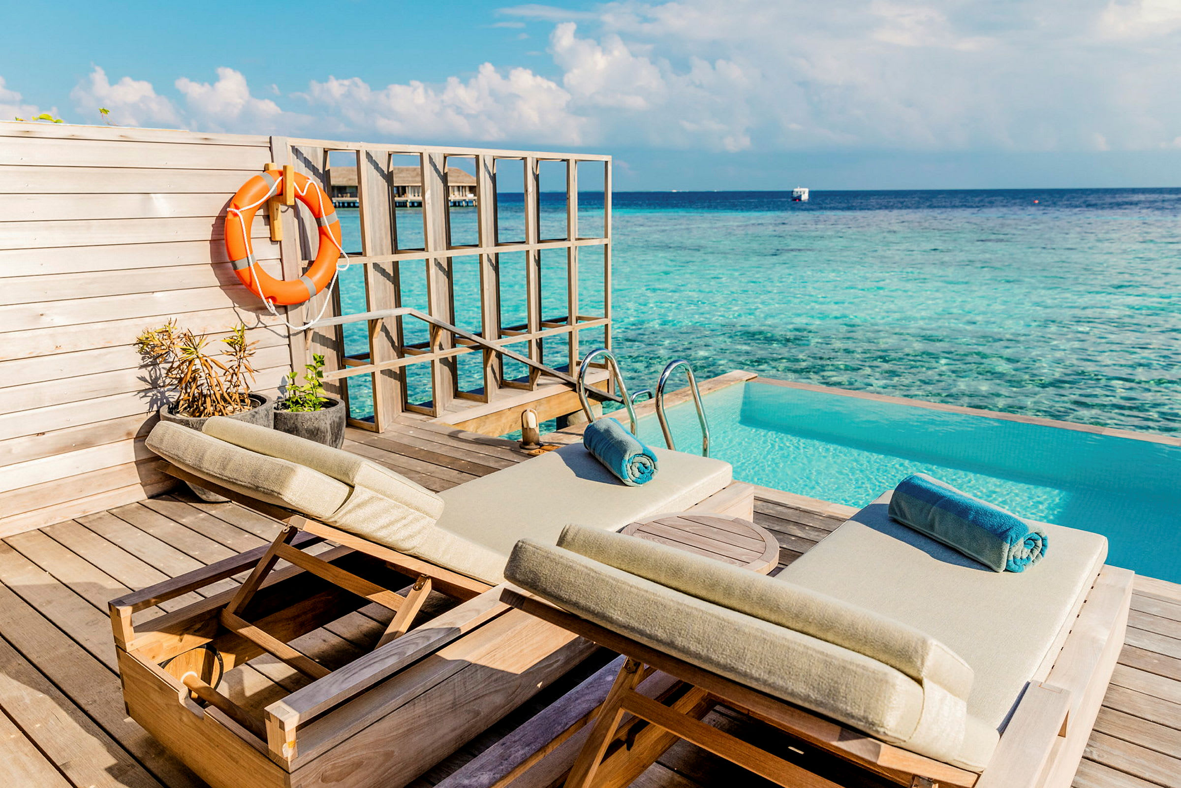 Två solstolar på en terrass vid en pool med utsikt över havet. (AI-genererad text)