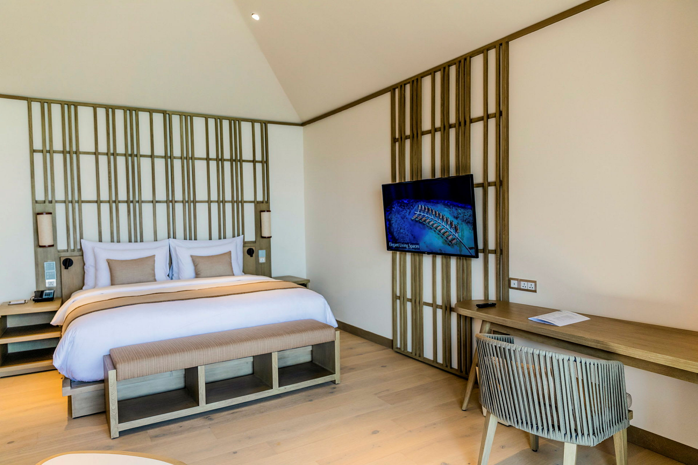 Ett hotellrum med en dubbelsäng, TV på väggen och skrivbord med stol. (AI-genererad text)