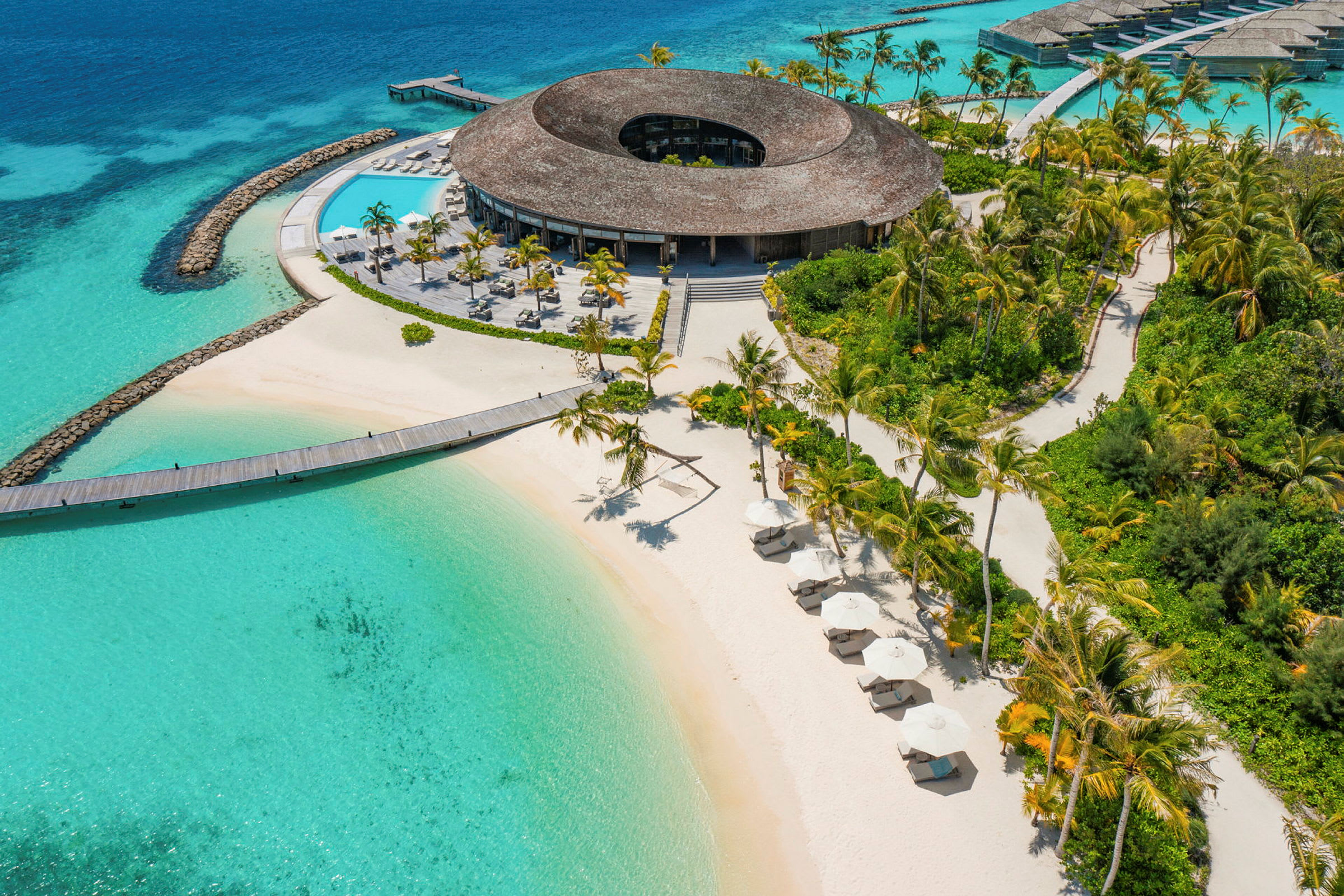 Flygfoto över en tropisk resort med sandstrand, turkost vatten och solstolar under parasoller. (AI-genererad text)