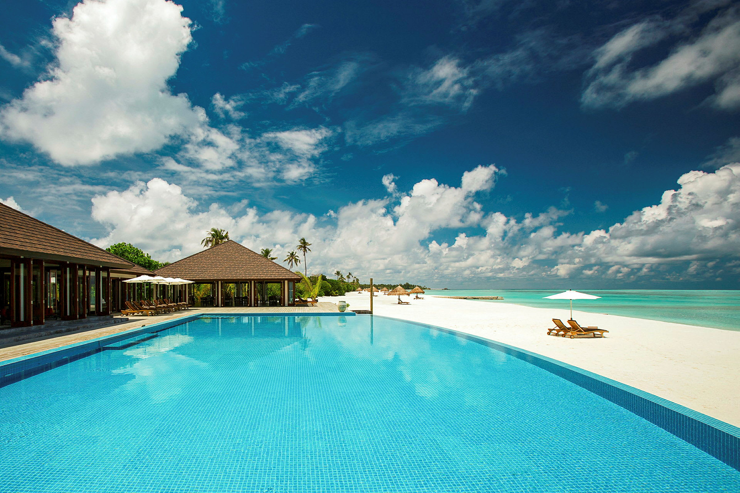 En lyxig resort med pool bredvid en vit sandstrand. (AI-genererad text)