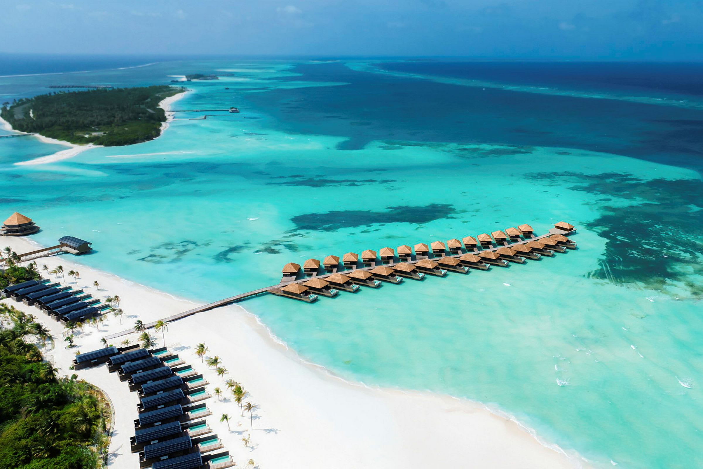Panoramautsikt över turkost vatten med övervattensbungalower och en sandstrand. (AI-genererad text)