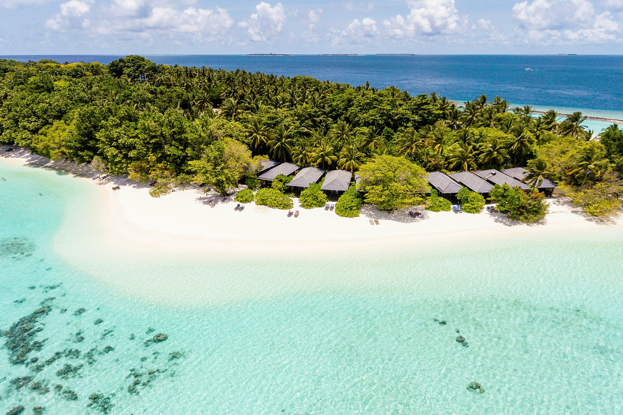 En tropisk strand med klart turkost vatten, bungalows och tät vegetation. (AI-genererad text)