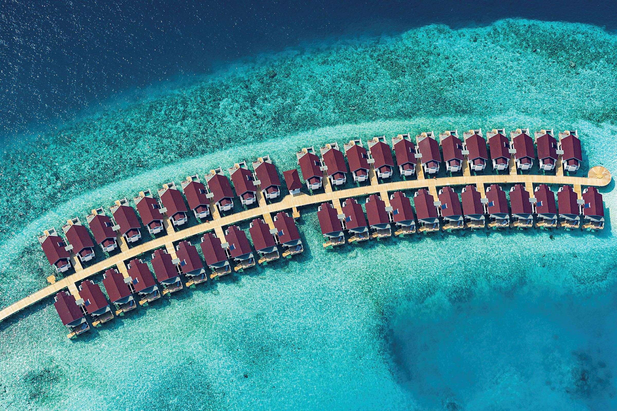 Flygbild av övervattensbungalower på rad i turkost vatten. (AI-genererad text)