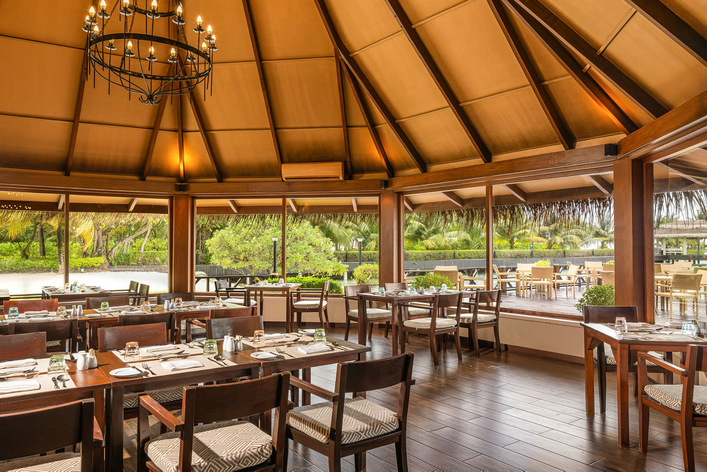 En restaurang med tak av trä, stora glasfönster och dukade bord. (AI-genererad text)