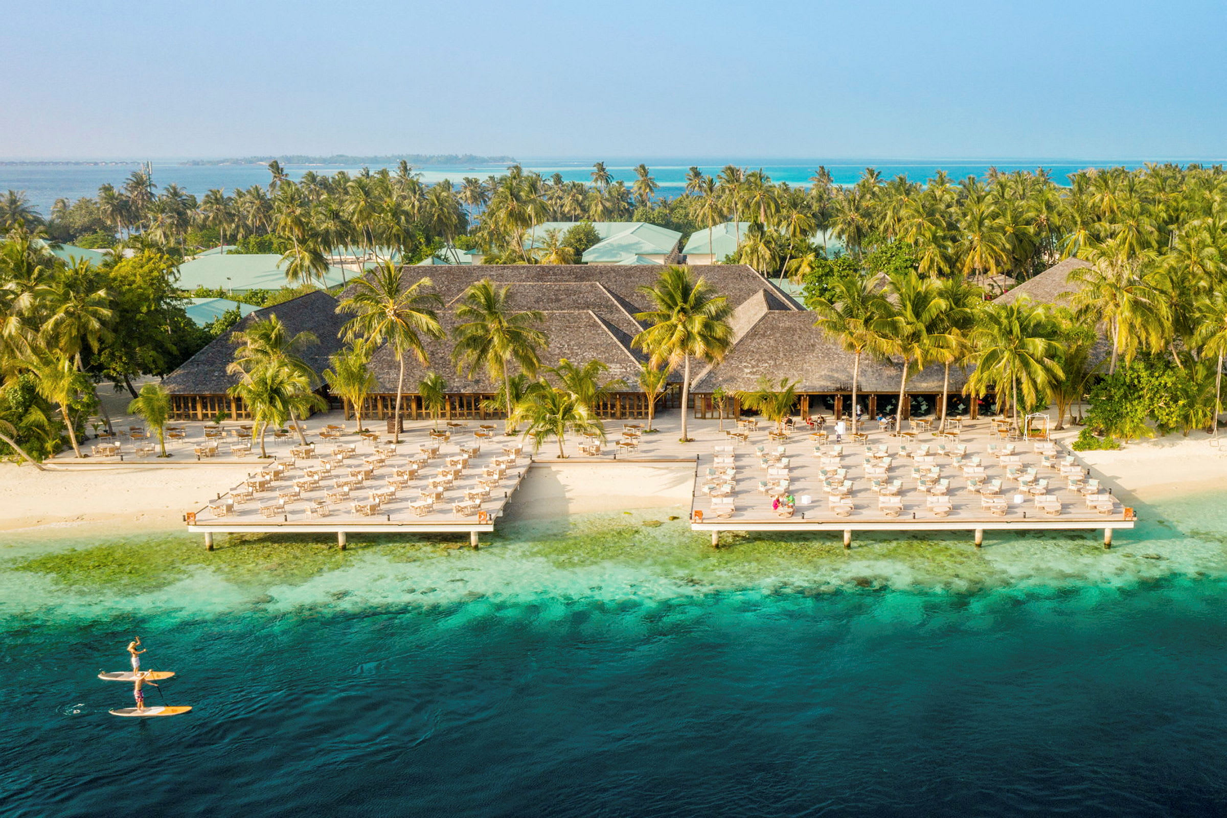 Hotellanläggning vid stranden med solstolar och turkosblått vatten. (AI-genererad text)