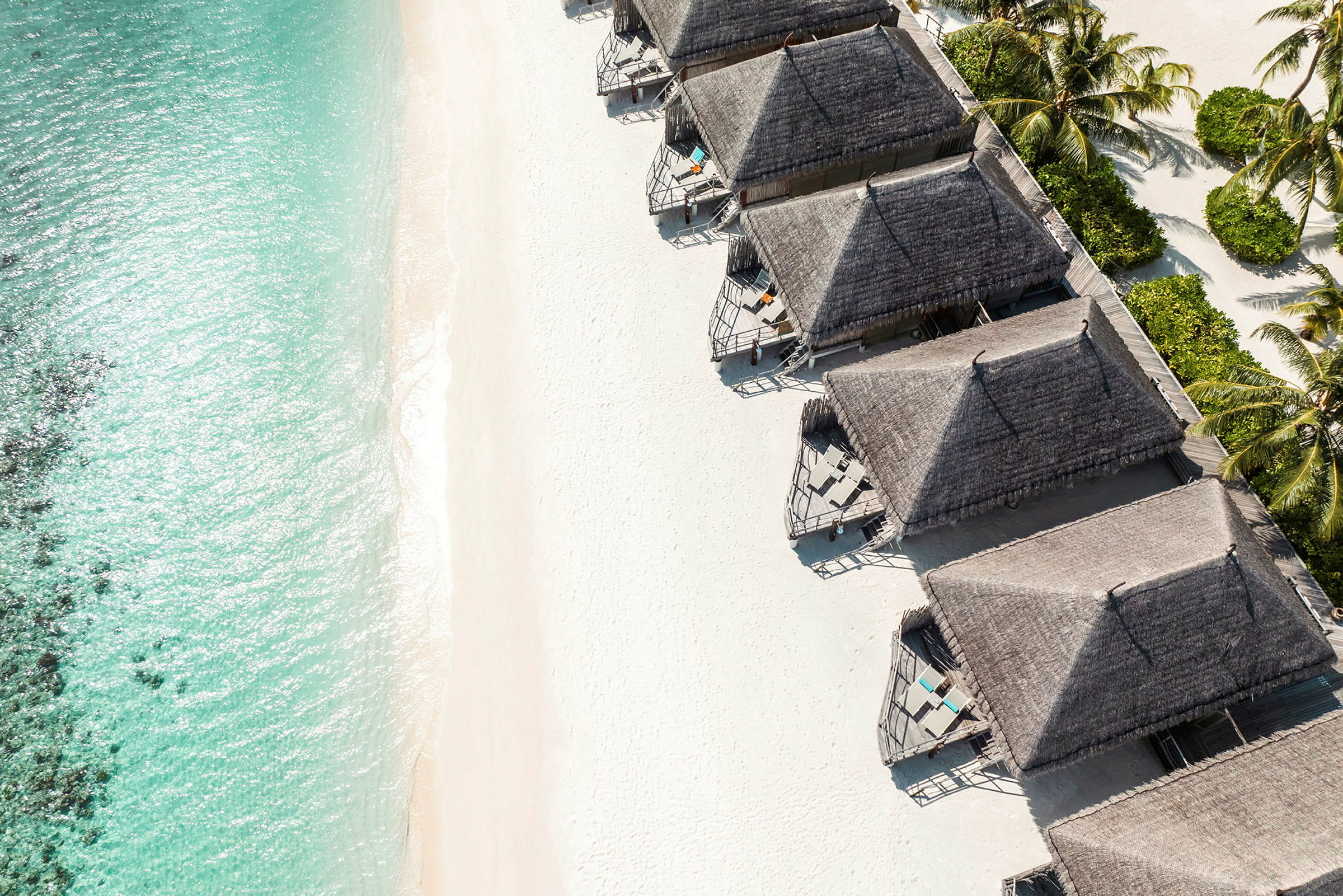 Strand med turkost vatten och flera strandnära bungalows. (AI-genererad text)