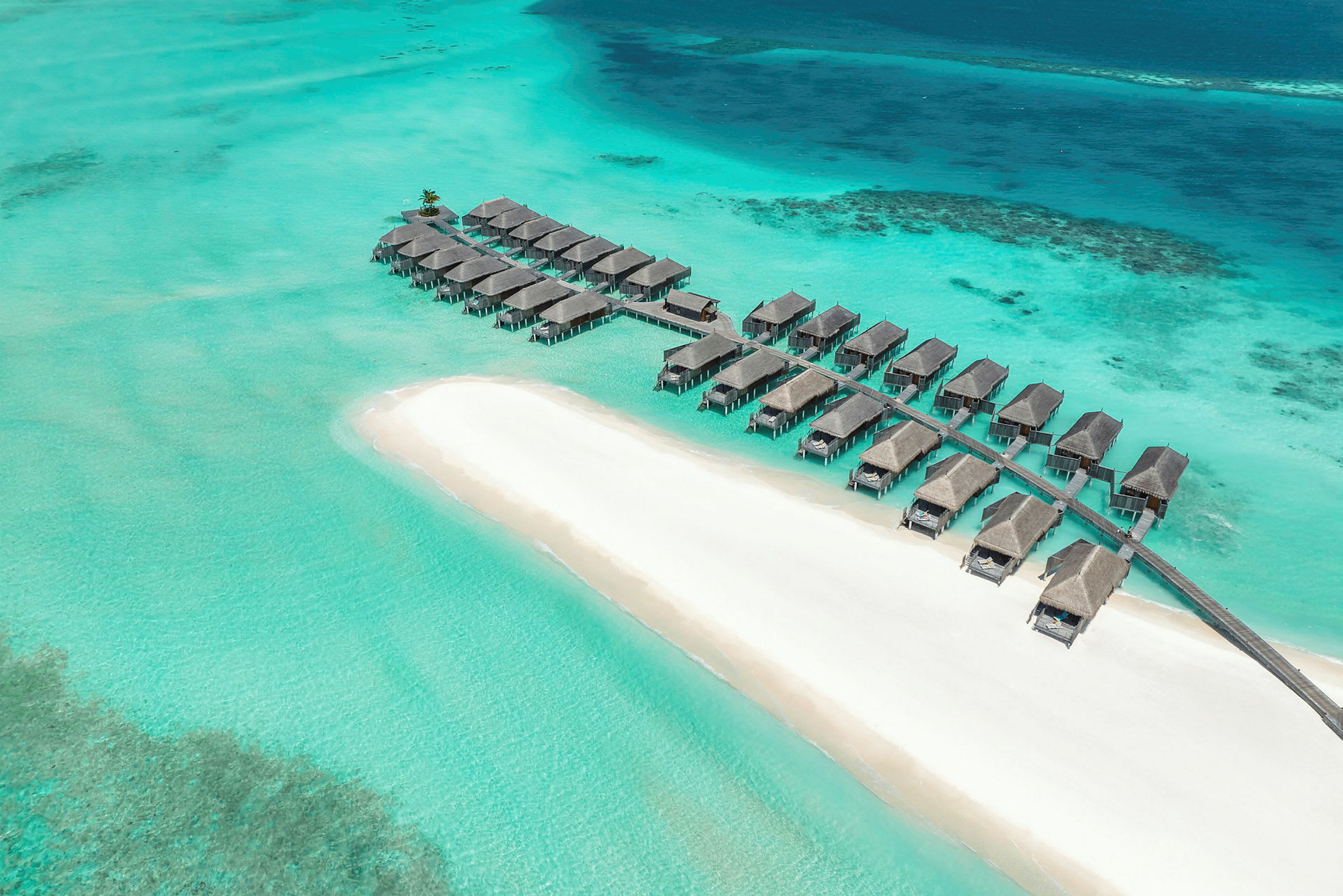 Bungalows på pelare ovanför klart turkost vatten vid en vit sandstrand. (AI-genererad text)