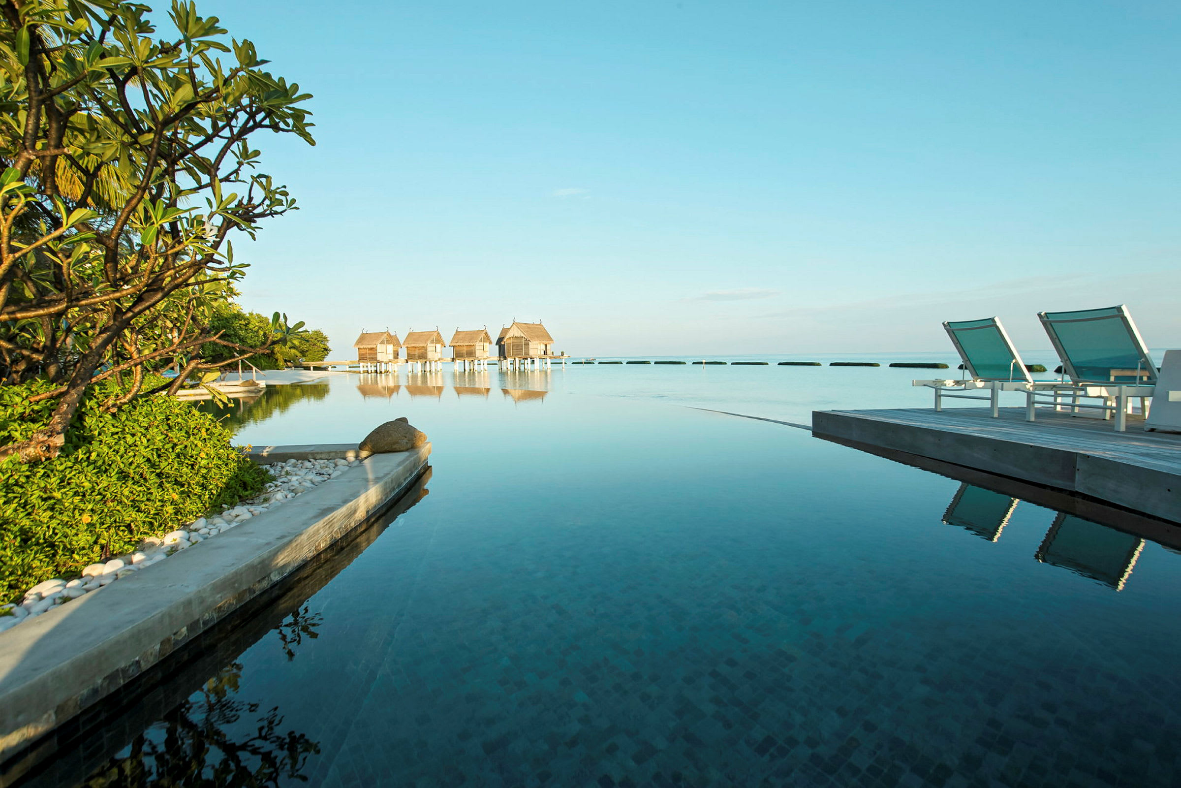 Strandnära stugor och solstolar vid en lugn pool. (AI-genererad text)