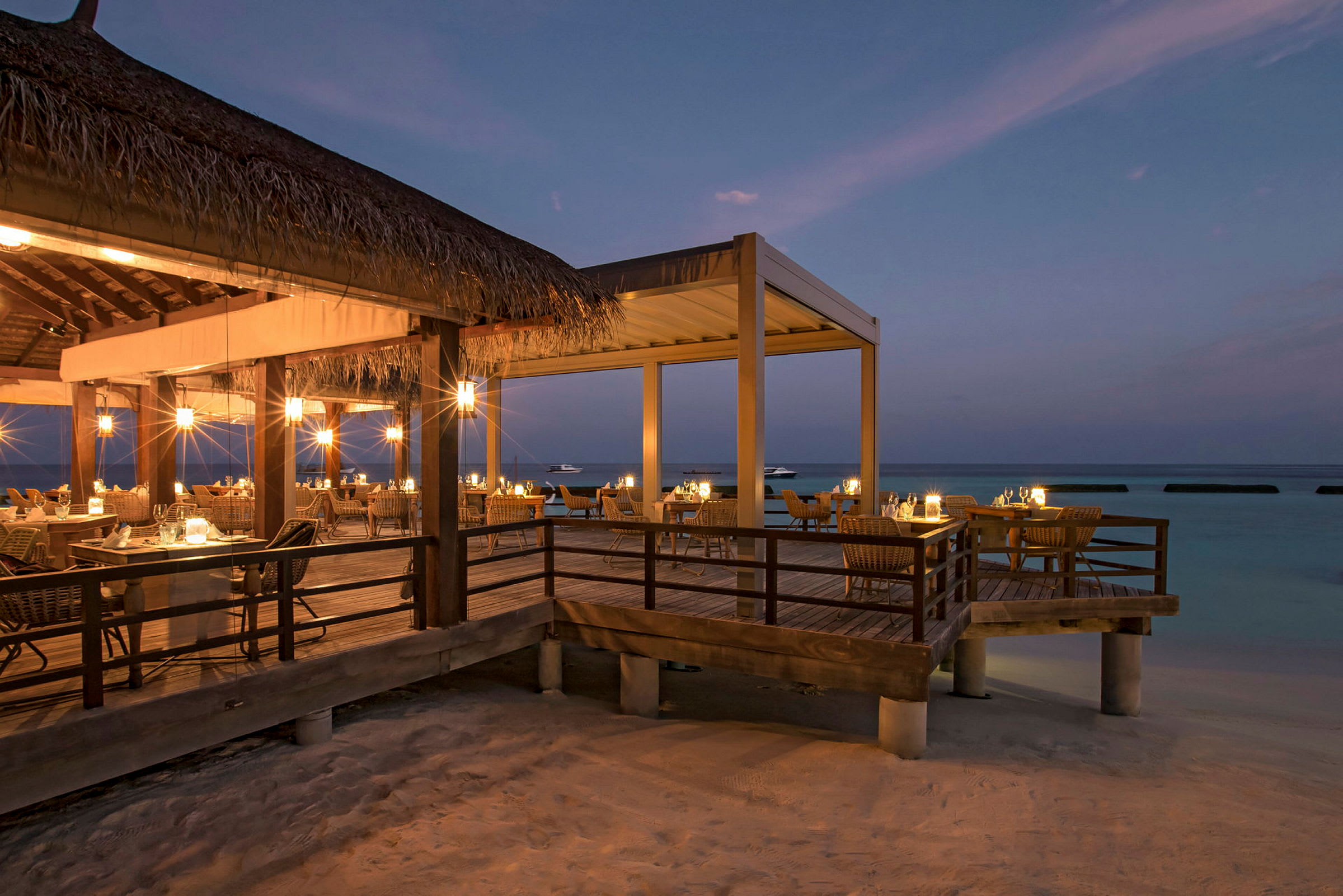 Restaurant med uteservering vid strand i skymning. (AI-genererad text)