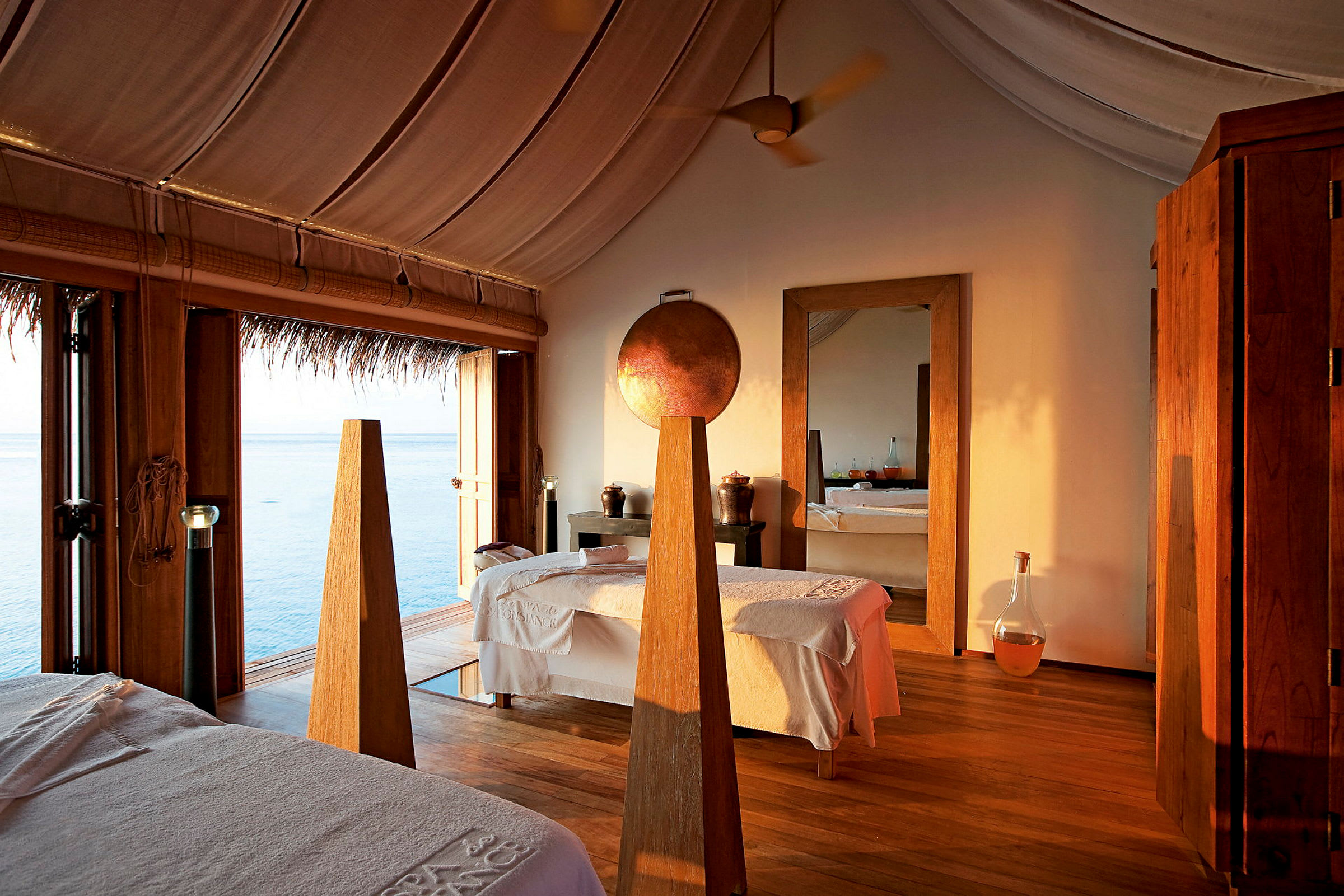 Interiör av ett spa med massagebänkar, trägolv och utsikt över havet. (AI-genererad text)