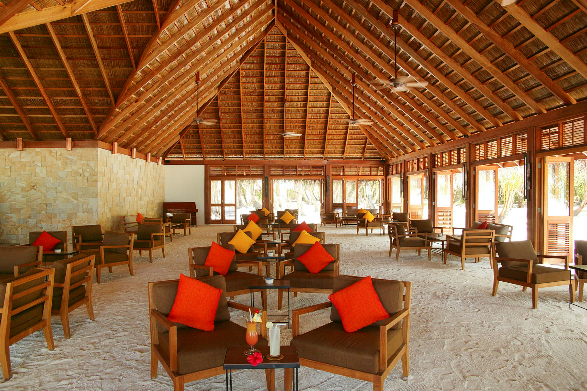 En öppen träpaviljong med sittgrupper och färgglada kuddar. (AI-genererad text)