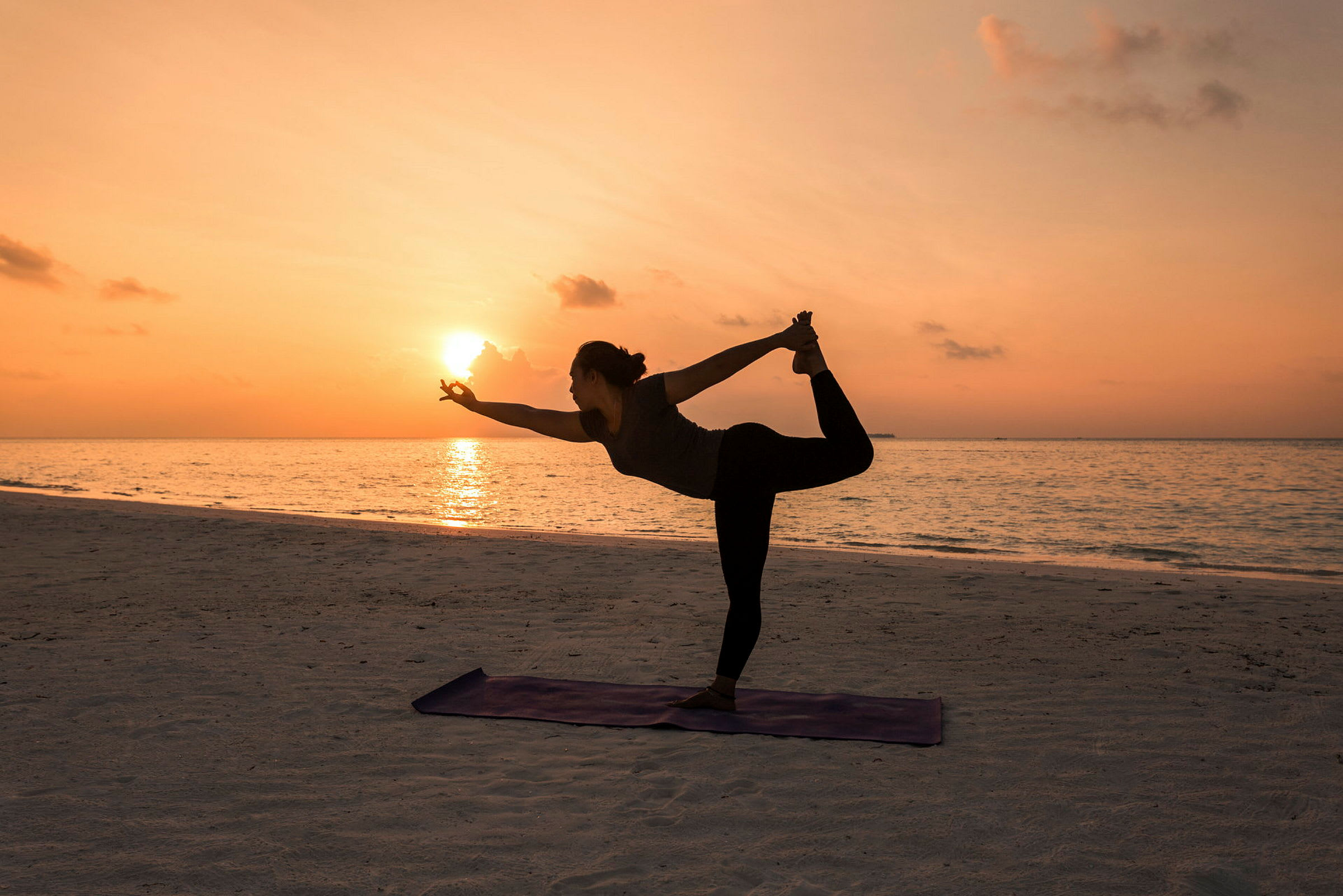 Silhuetten av en person som utför yoga vid stranden under solnedgången. (AI-genererad text)