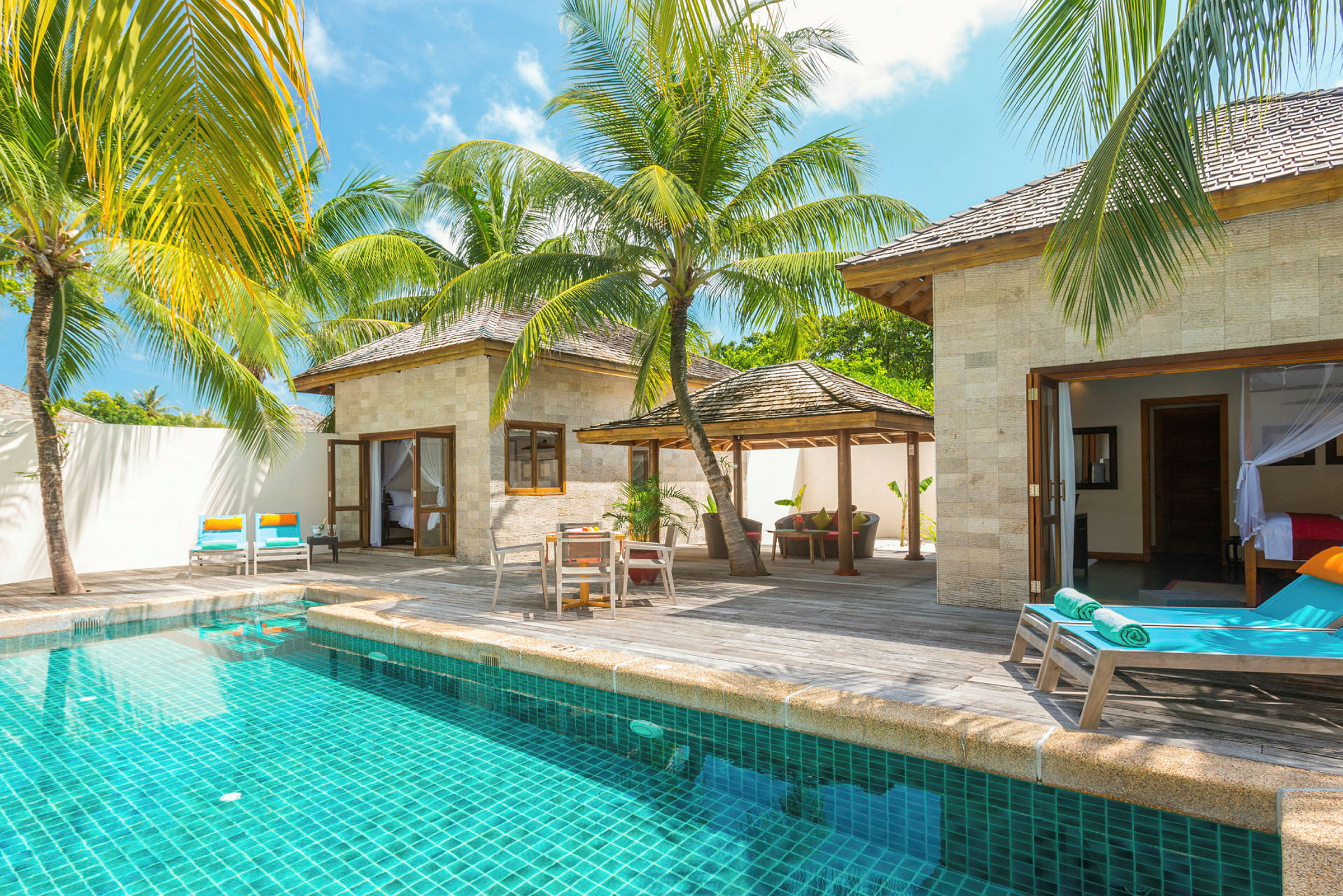 En villa med privat pool, omgiven av solstolar och tropiska palmer. (AI-genererad text)