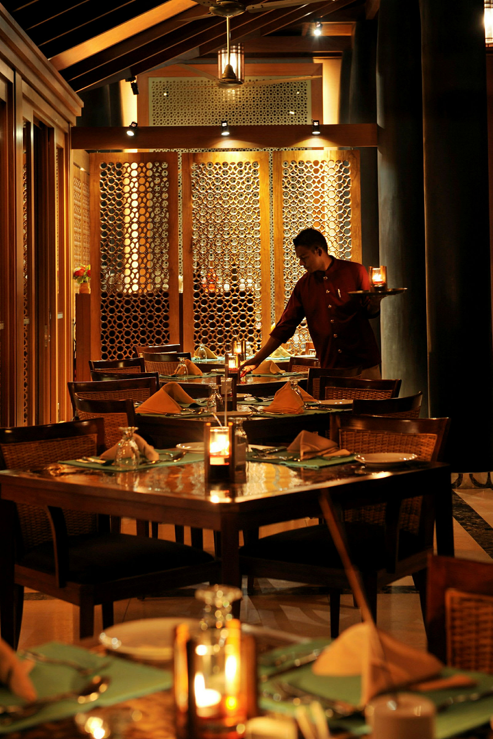 En välupplyst restaurang med dukade bord och en person som serverar. (AI-genererad text)