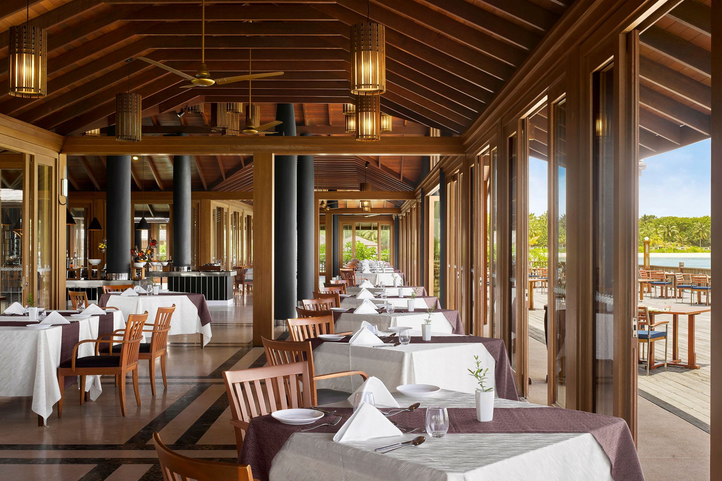 En restaurang med dukade bord och stora fönster med utsikt mot en veranda. (AI-genererad text)