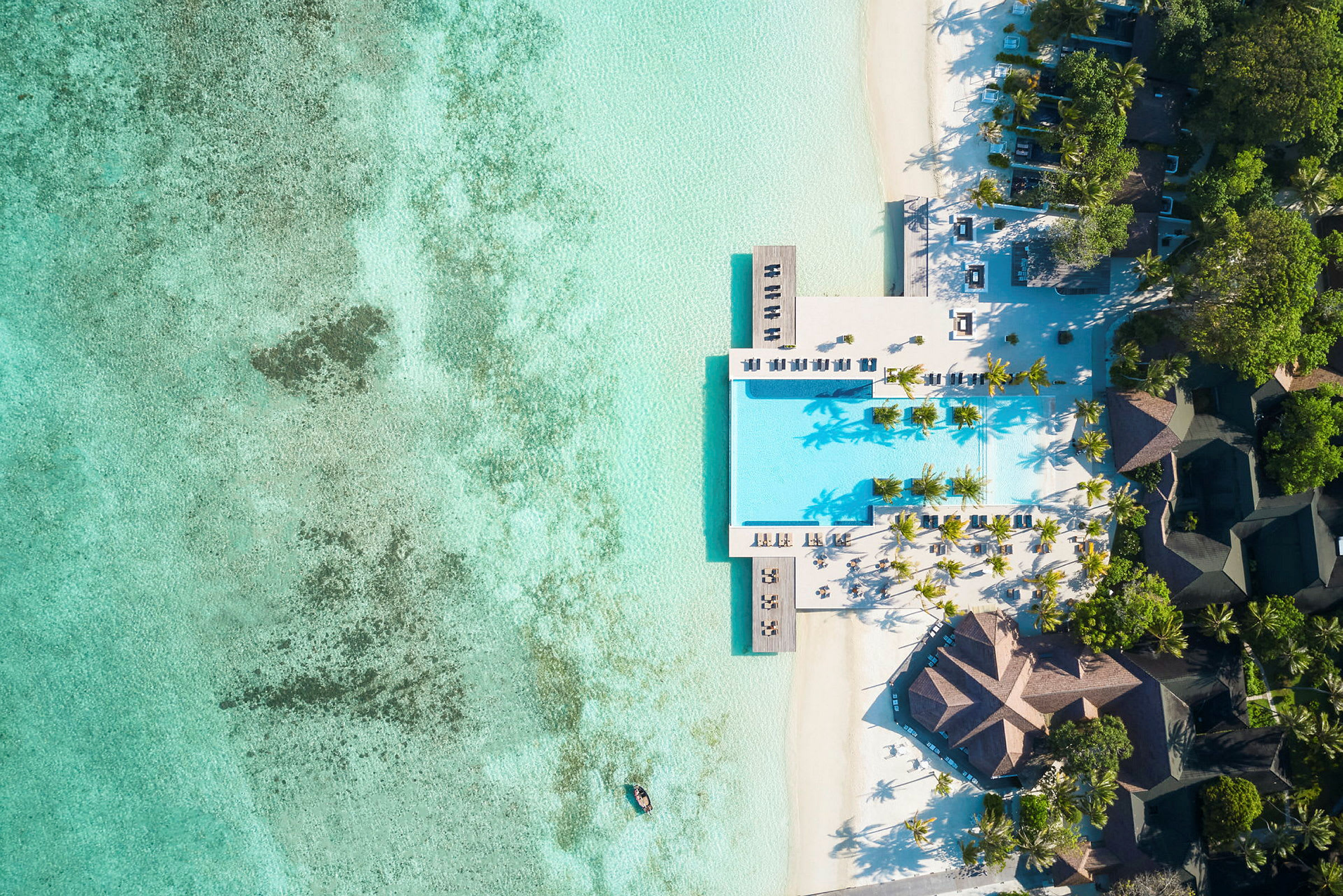 Flygfoto av ett lyxigt strandresort med pool, vita sandstränder och turkost vatten. (AI-genererad text)