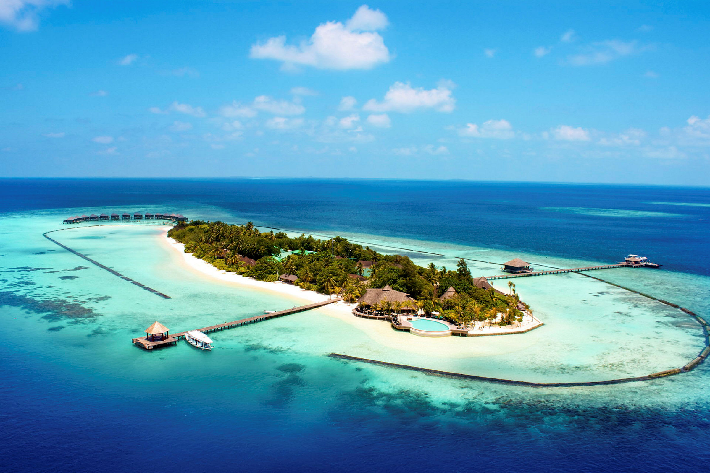 En liten tropisk ö omgiven av turkost hav, med stränder och bungalower. (AI-genererad text)