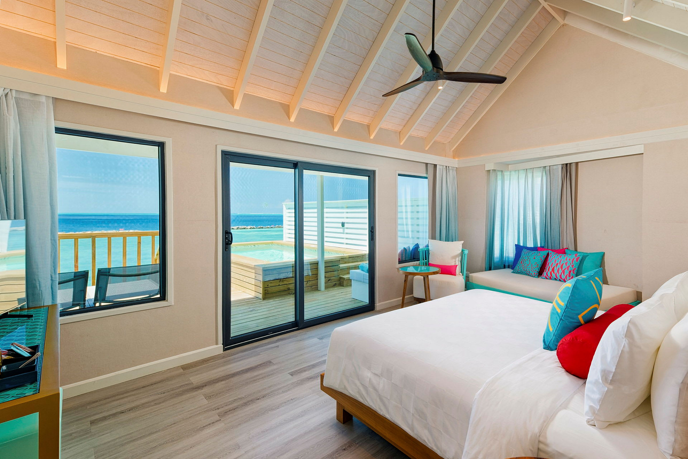 Ett sovrum med stora fönster och utsikt mot havet, samt en anslutande terrass med pool. (AI-genererad text)