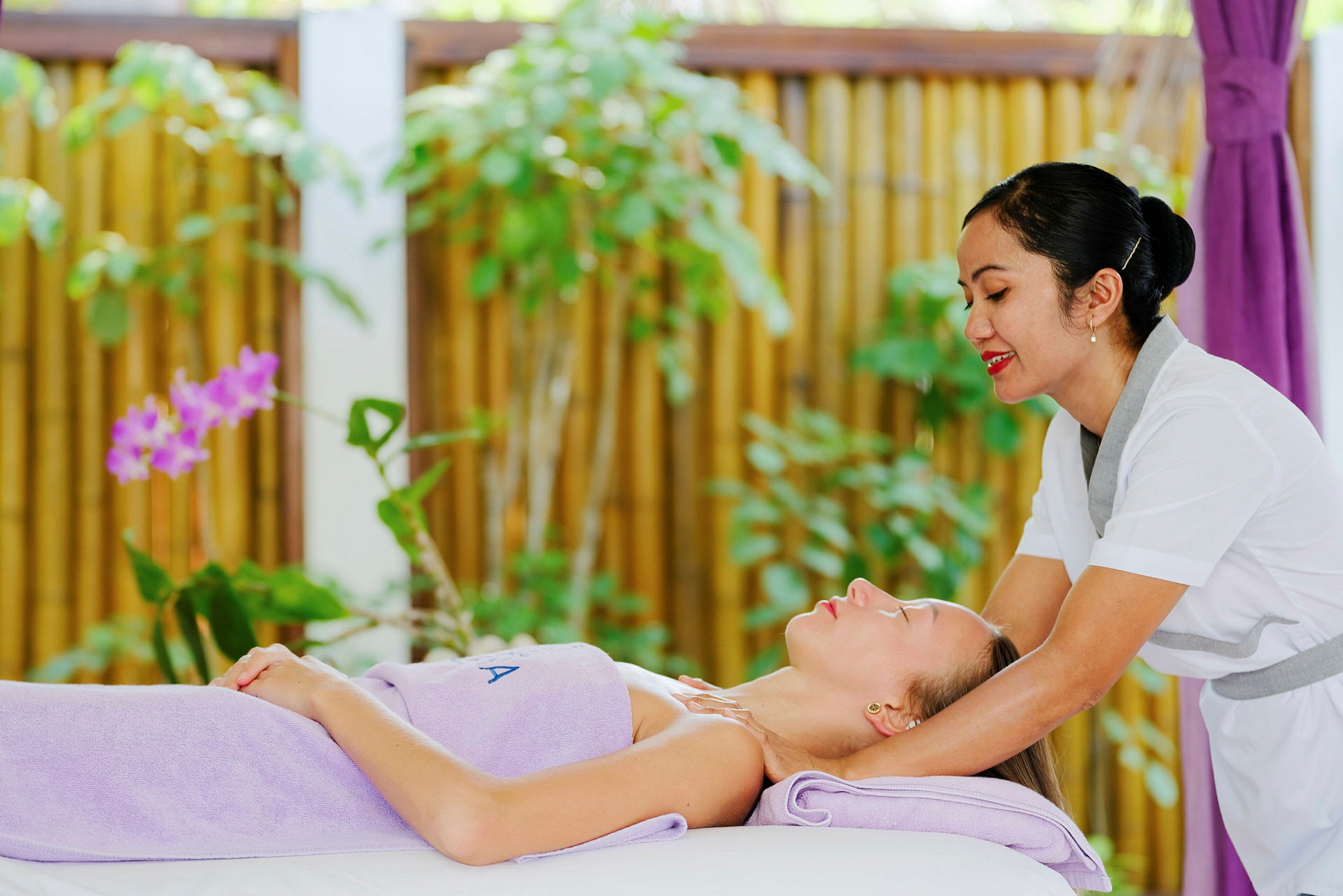 Massageterapeut utför behandling utomhus, omgiven av grönska. (AI-genererad text)
