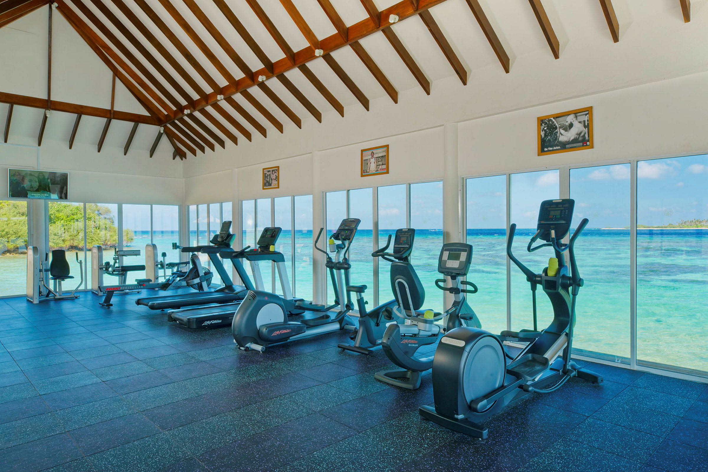 Gym med träningsmaskiner och utsikt över havet genom stora glasfönster. (AI-genererad text)