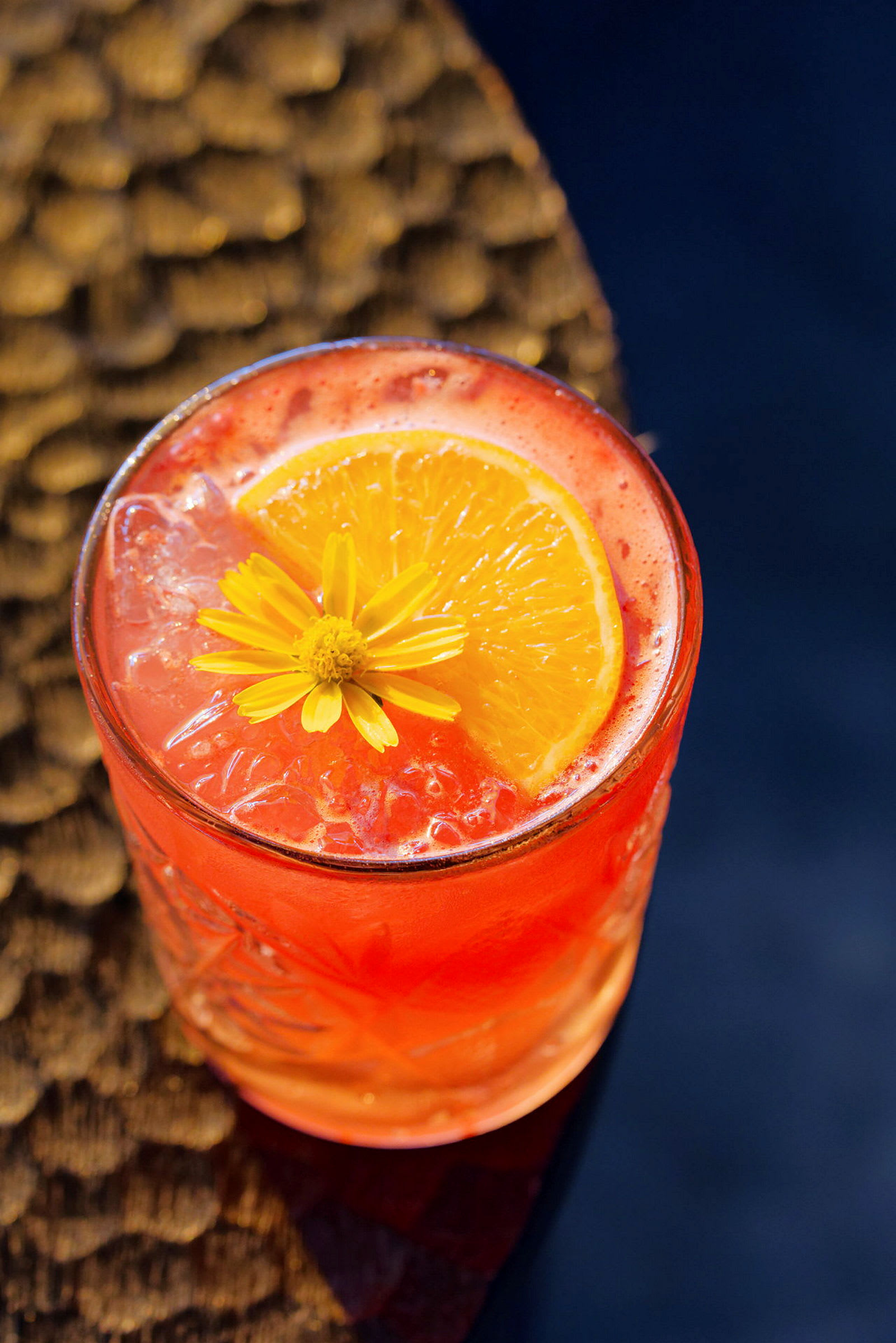 En orange drink serverad i ett glas dekorerat med en citrusskiva och blomma. (AI-genererad text)