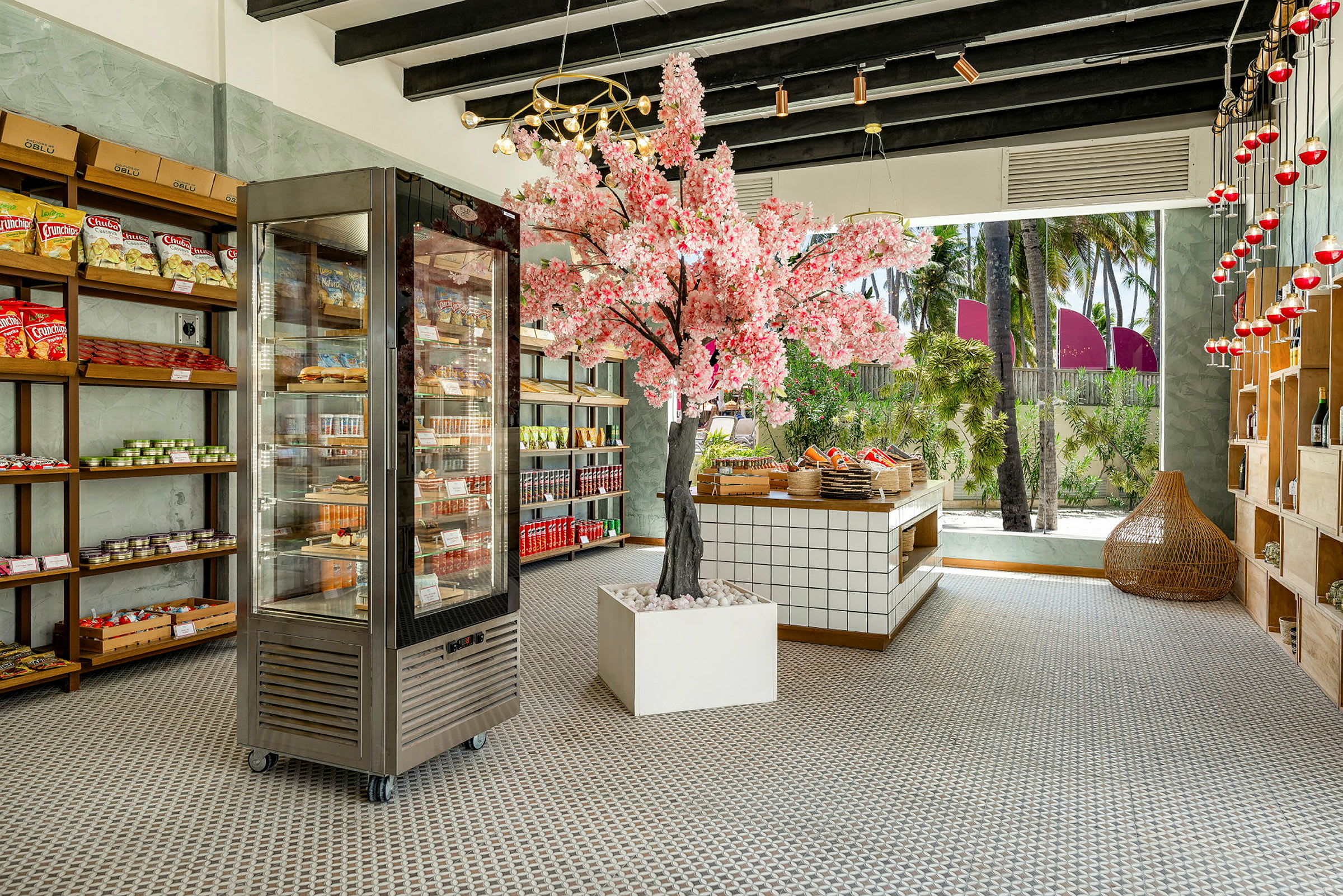 En inomhusbutik med en rosa blommig träddekoration, hyllor fyllda med varor och ett kylskåp. (AI-genererad text)