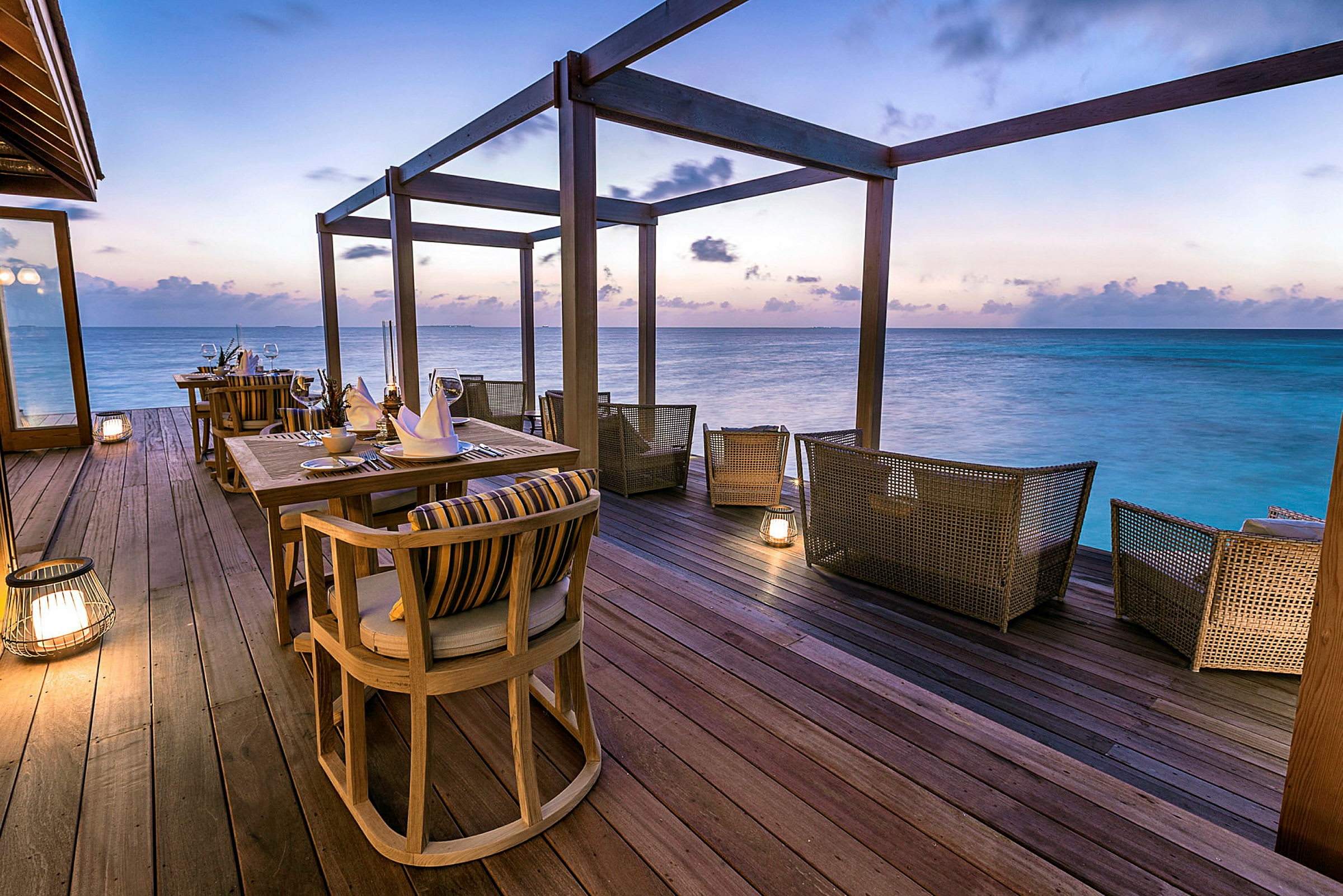 Exklusiv restaurang vid havet med sittplatser och dukning på en altan. (AI-genererad text)