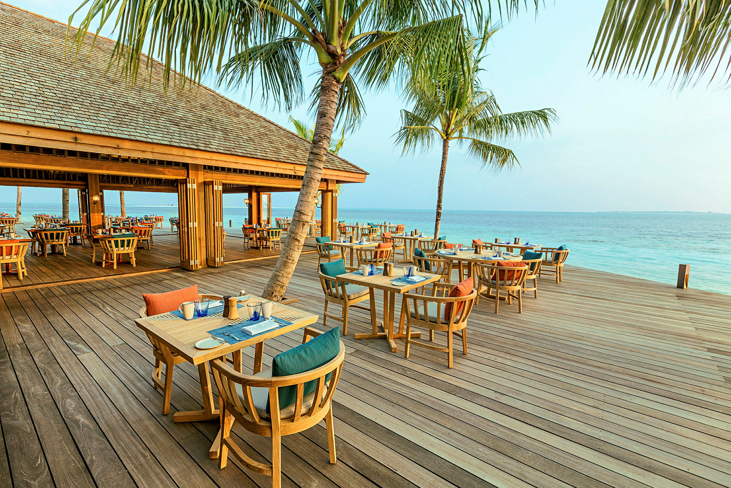 Restaurang vid stranden med utomhusbord under palmträd. (AI-genererad text)