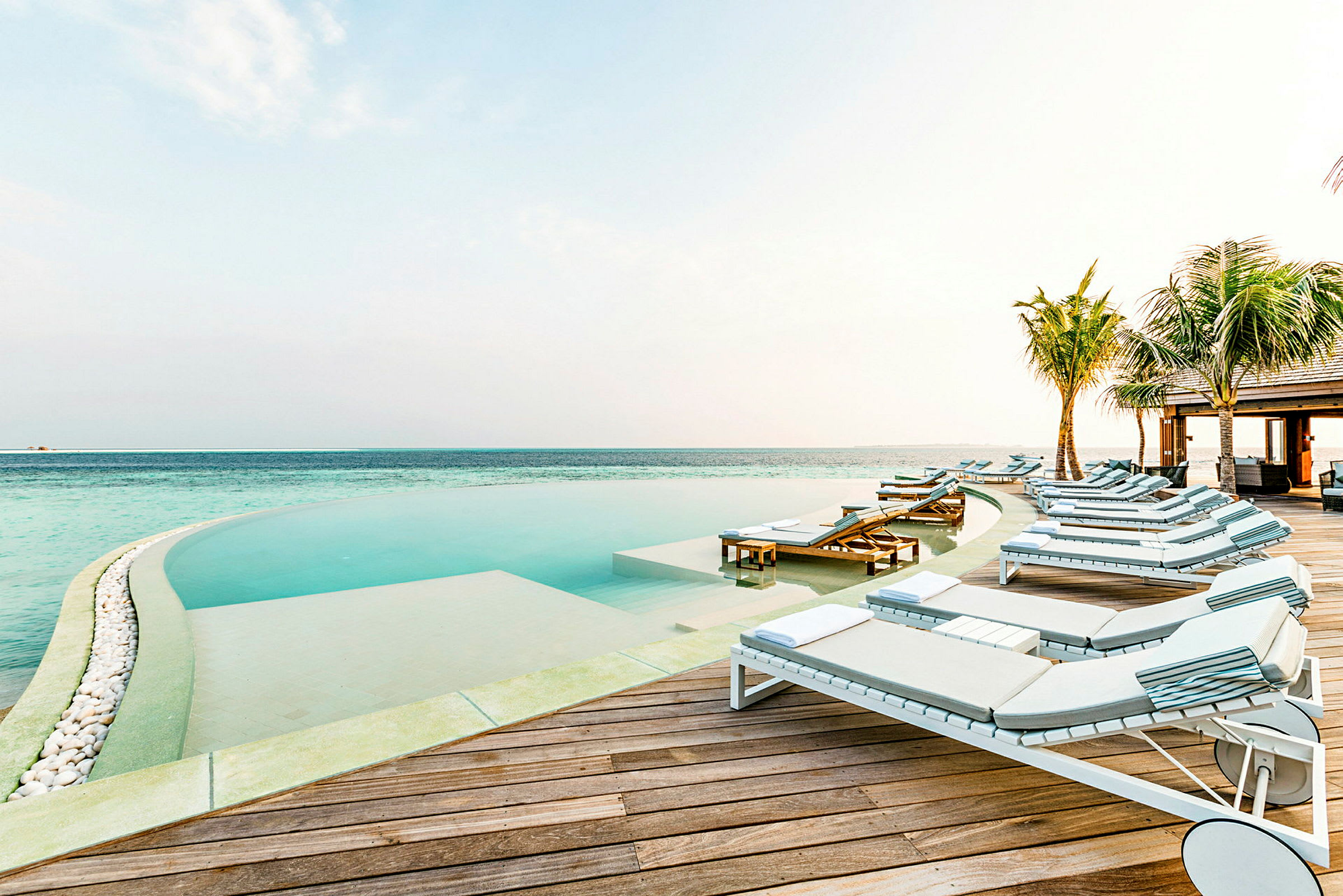 Solstolar vid en infinitypool nära havet. (AI-genererad text)
