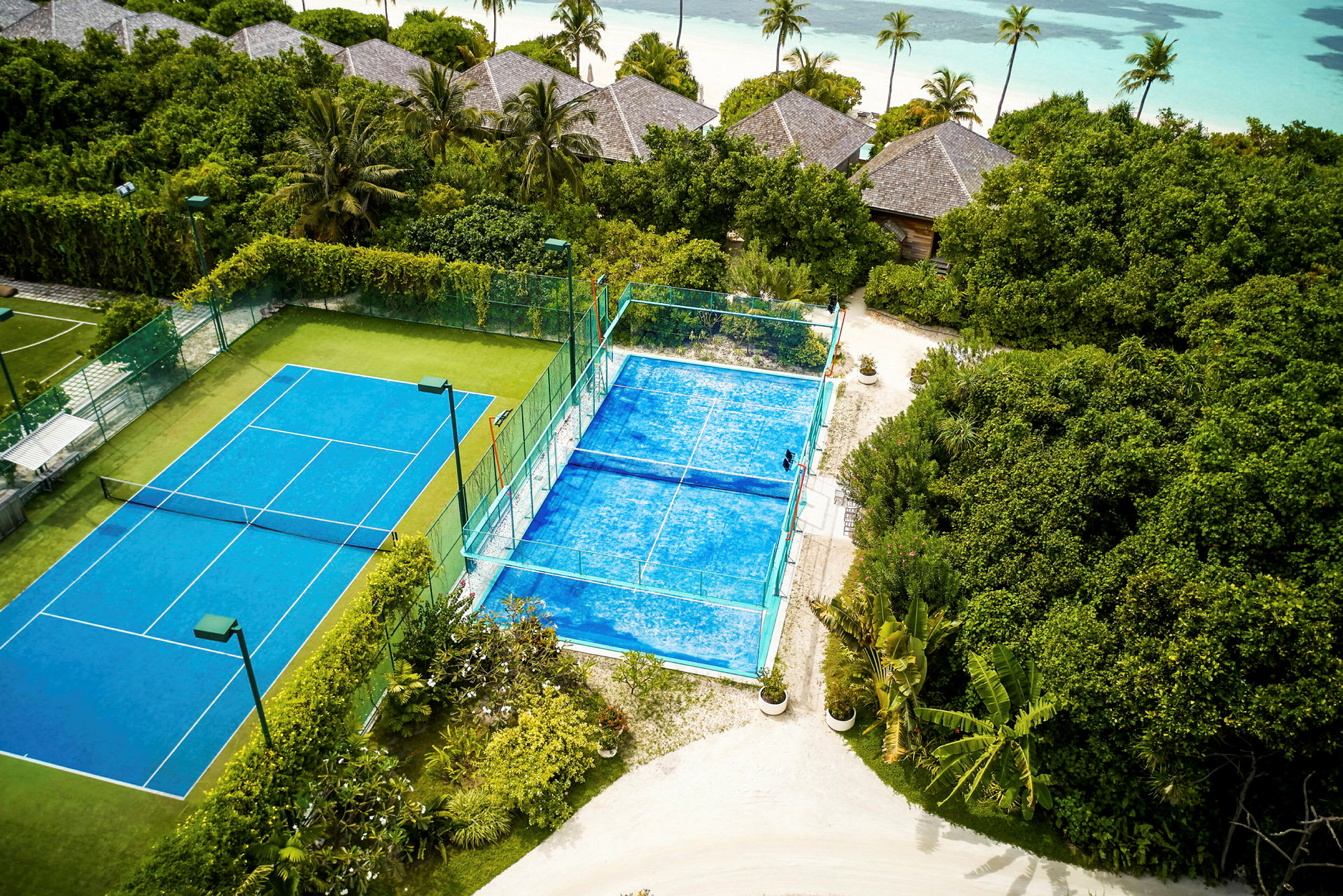 Två tennisplaner bland grönska nära stranden. (AI-genererad text)