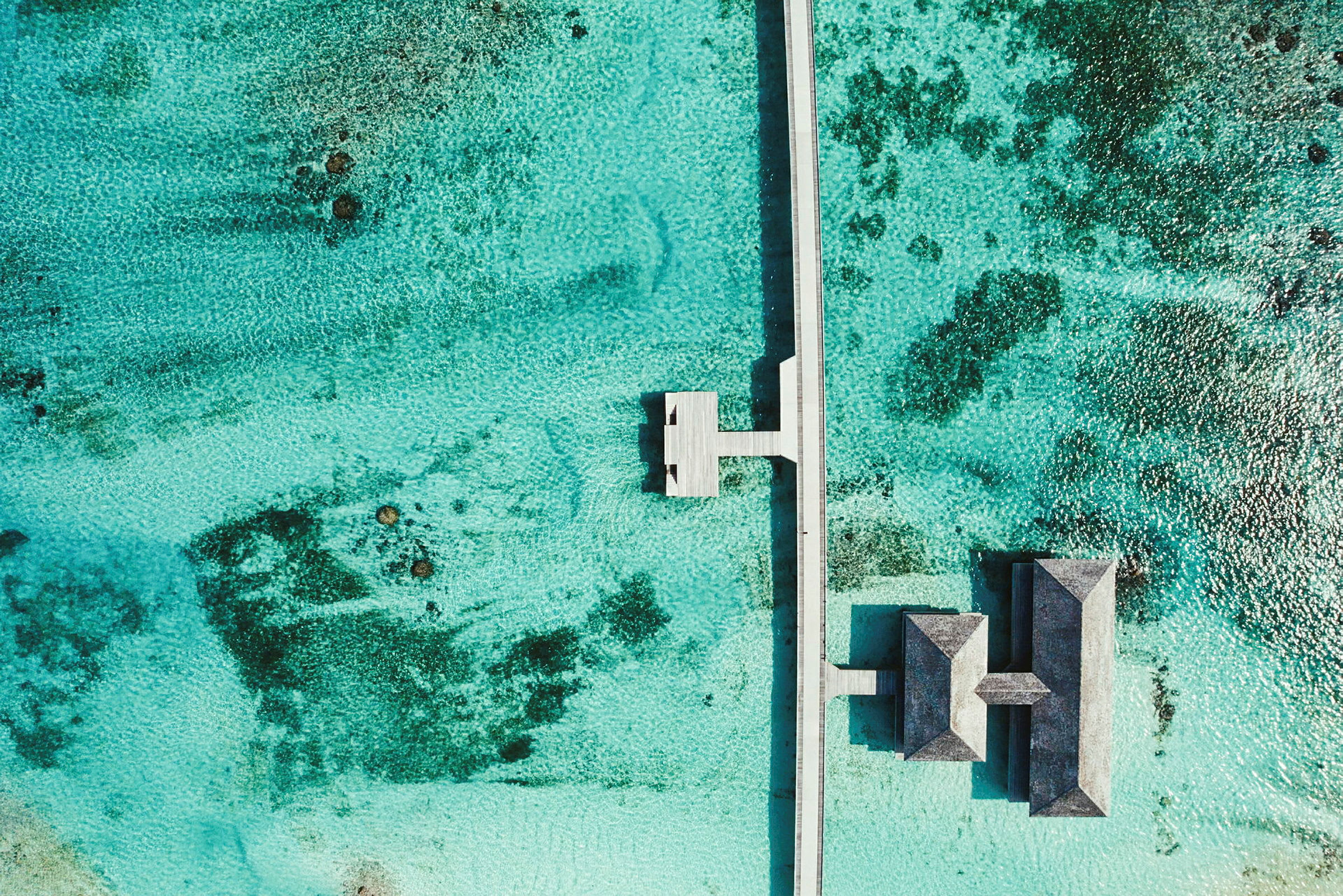Luftfoto av en brygga och övervattensbungalower omgivna av turkost vatten. (AI-genererad text)