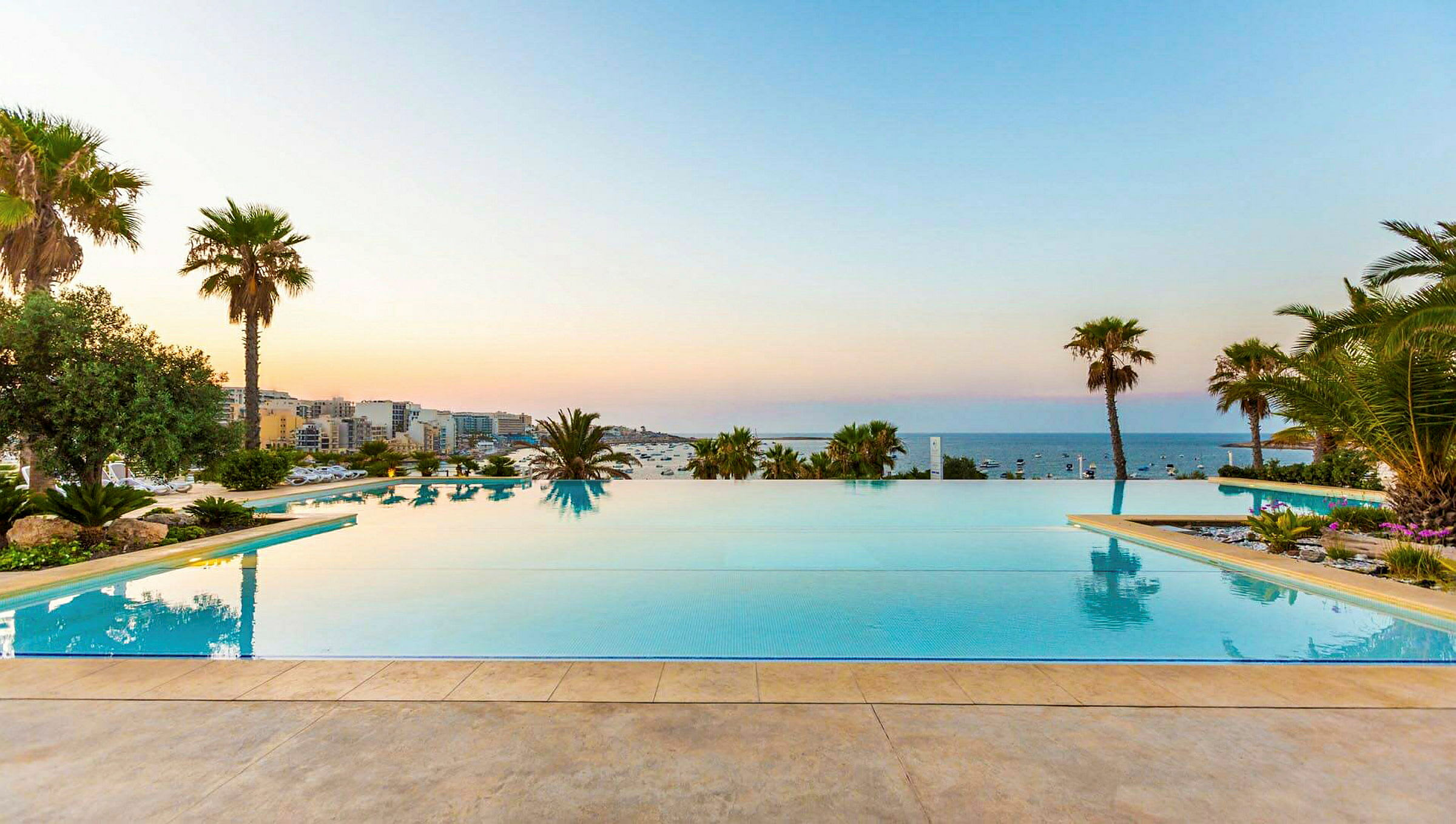 Infinitypool med utsikt över havet, omgiven av palmträd och grönska. (AI-genererad text)