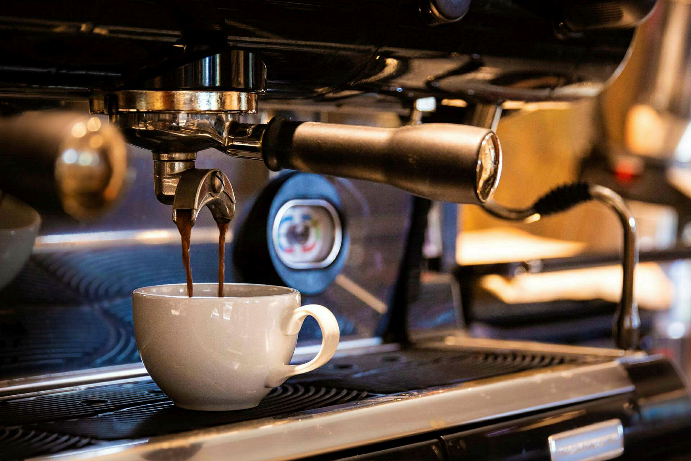 En espressomaskin brygger kaffe som rinner ner i en vit kopp. (AI-genererad text)