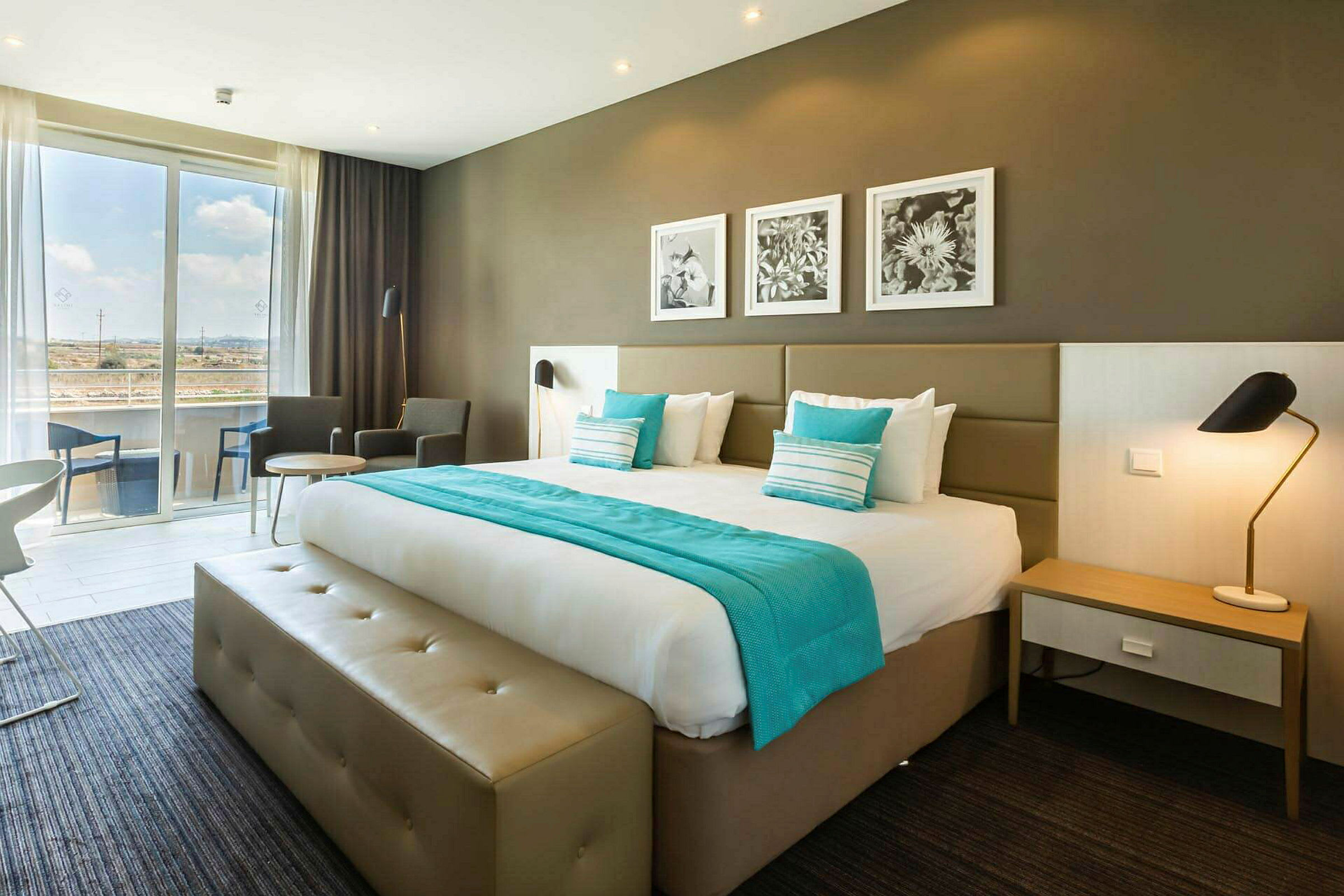 Hotellrum med en dubbelsäng, sittområde och stora fönster. (AI-genererad text)