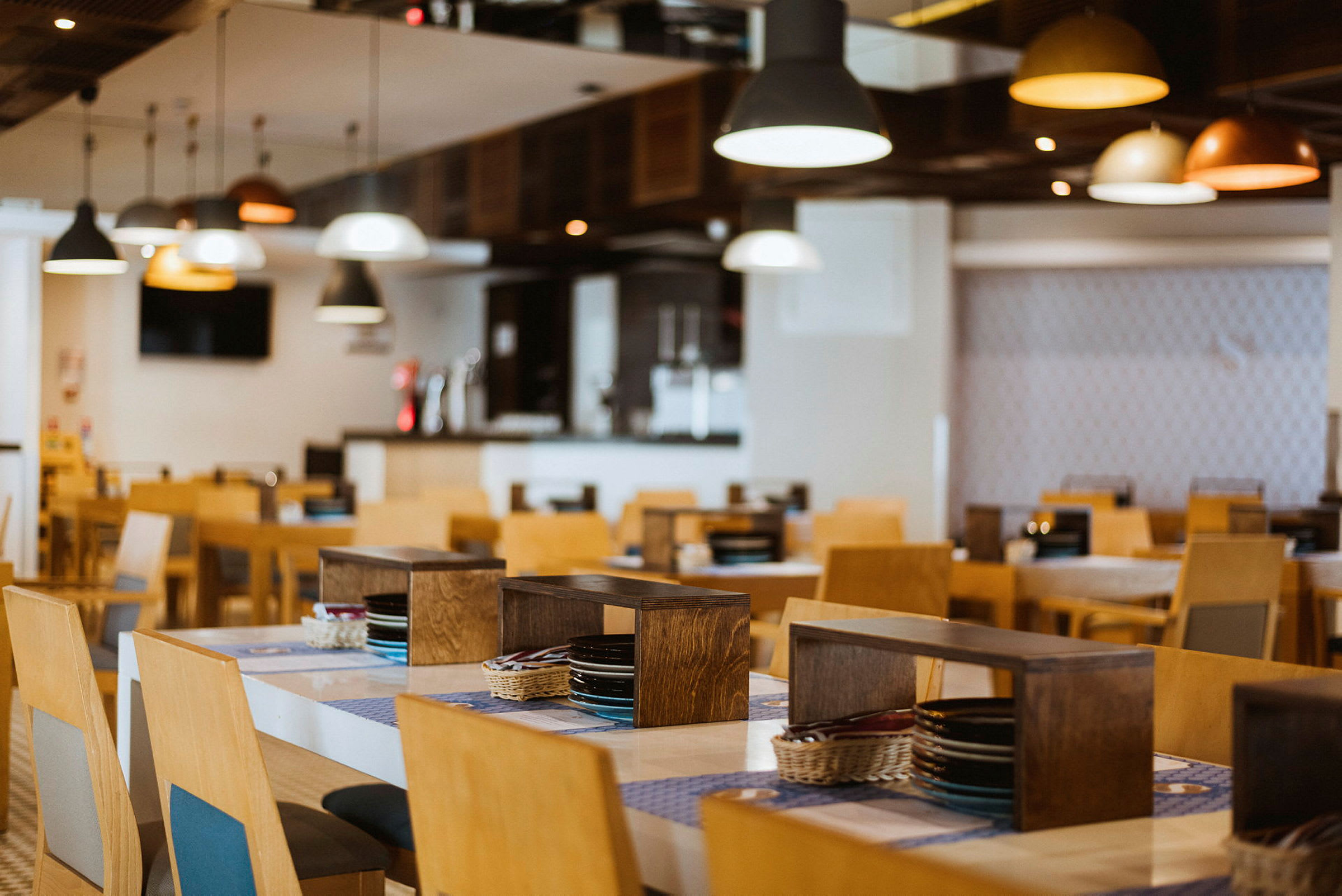 Restaurang med träbord och stolar, upplyst av taklampor. (AI-genererad text)