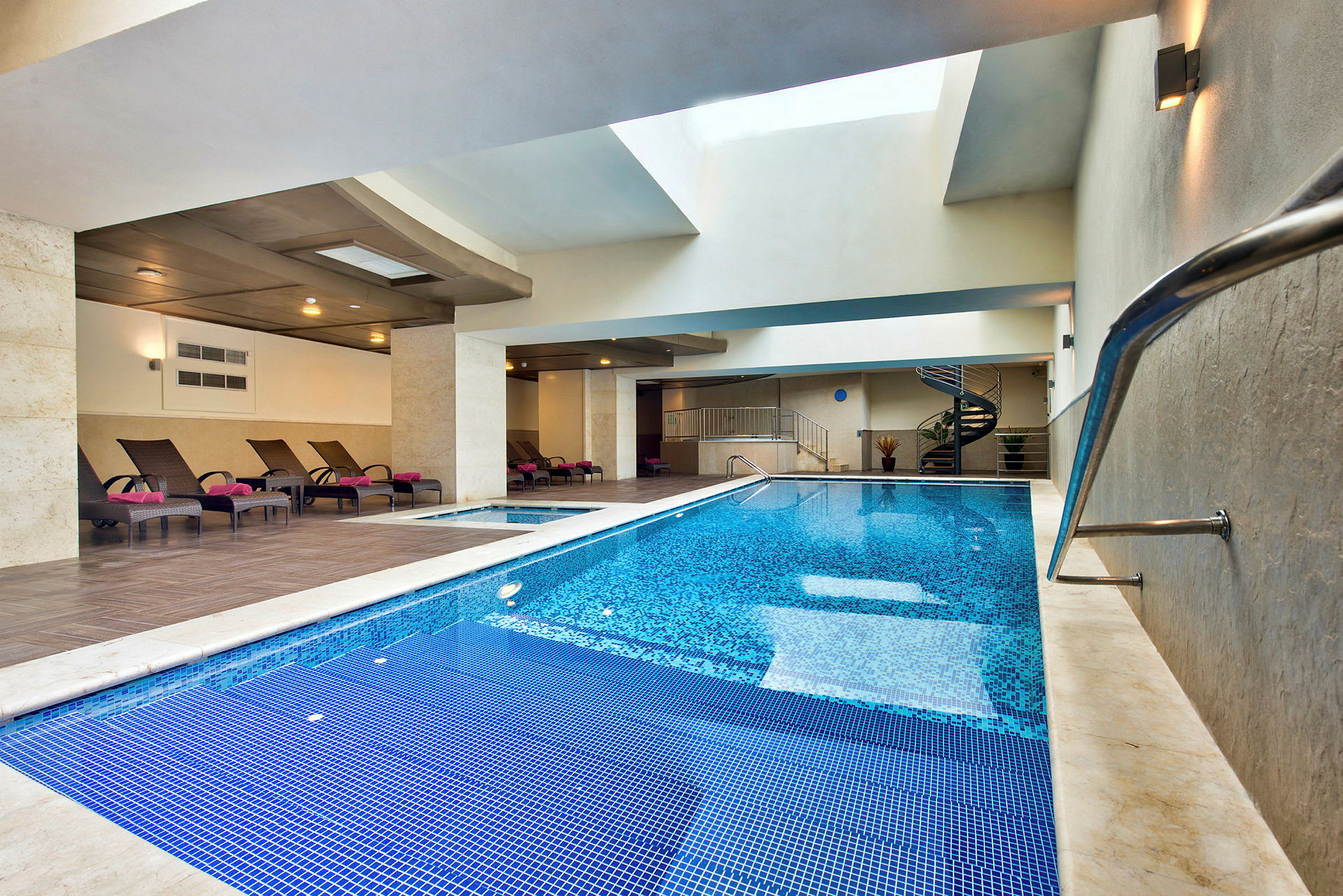 Inomhuspool med solstolar och modern design. (AI-genererad text)