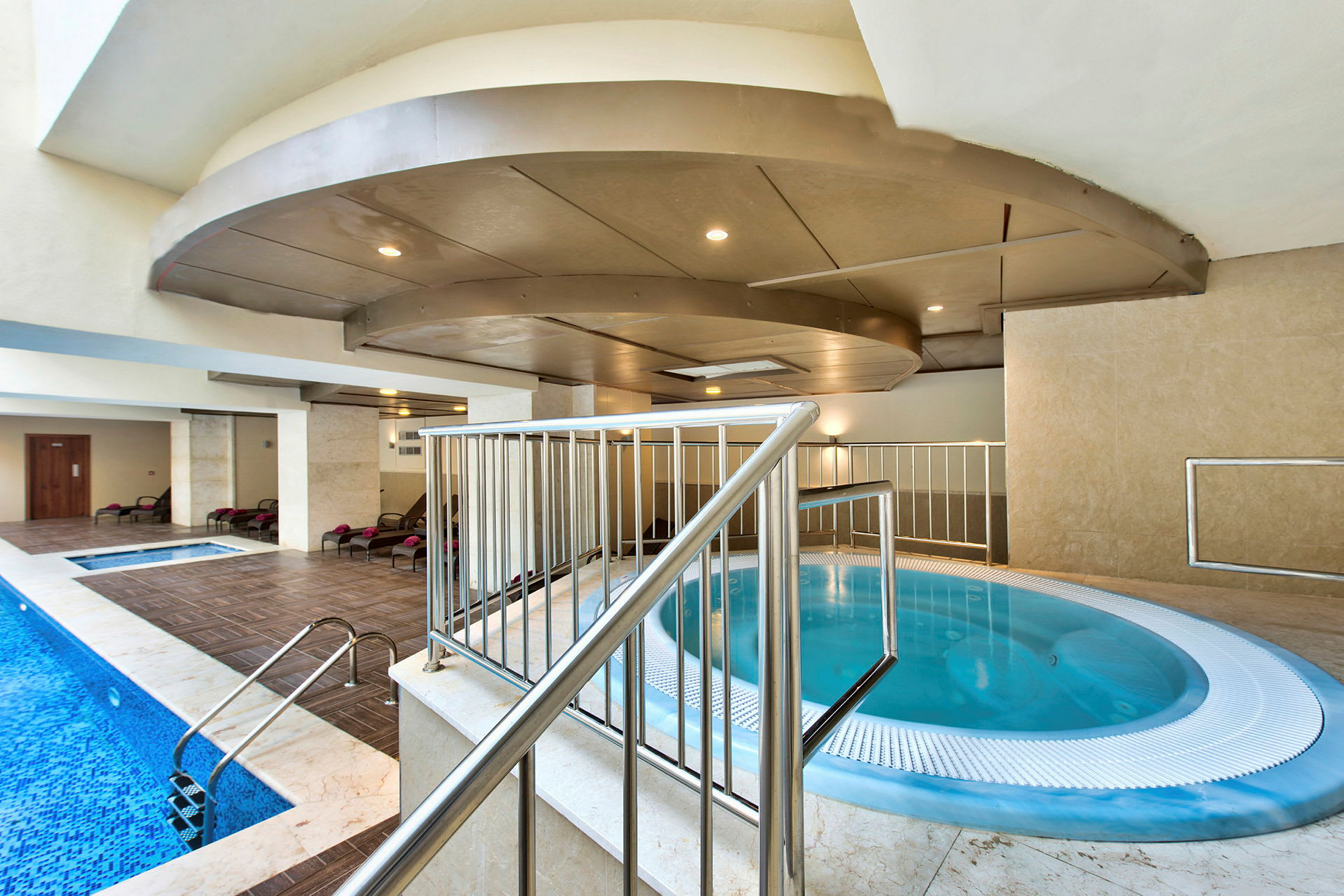 En inomhuspool med jacuzzi och vilstolar. (AI-genererad text)