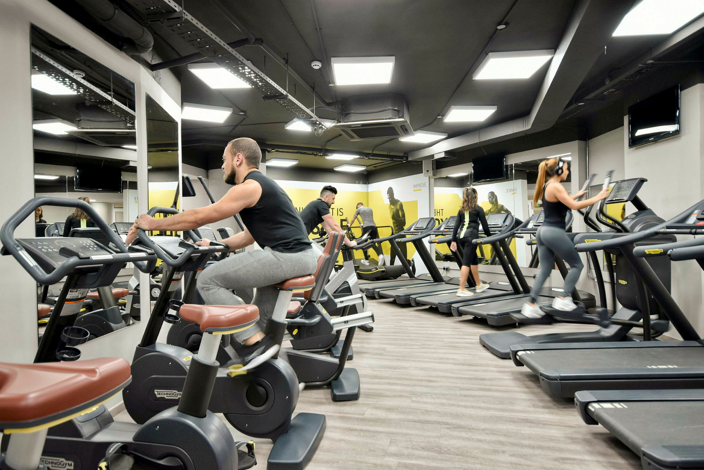 Ett gym med träningsutrustning och personer som tränar. (AI-genererad text)