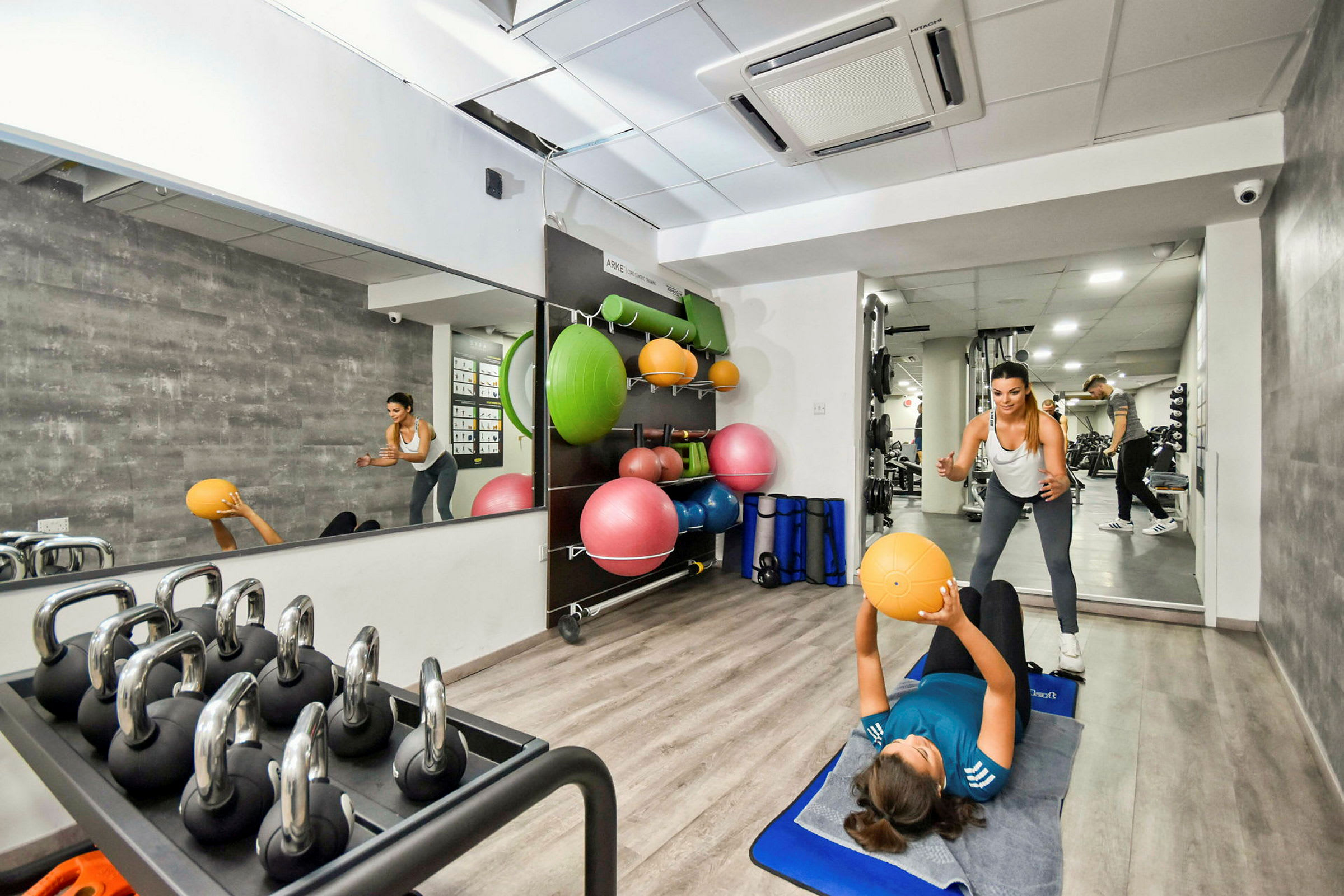 Ett inomhusgym med träningskulor, hantlar och speglar. (AI-genererad text)