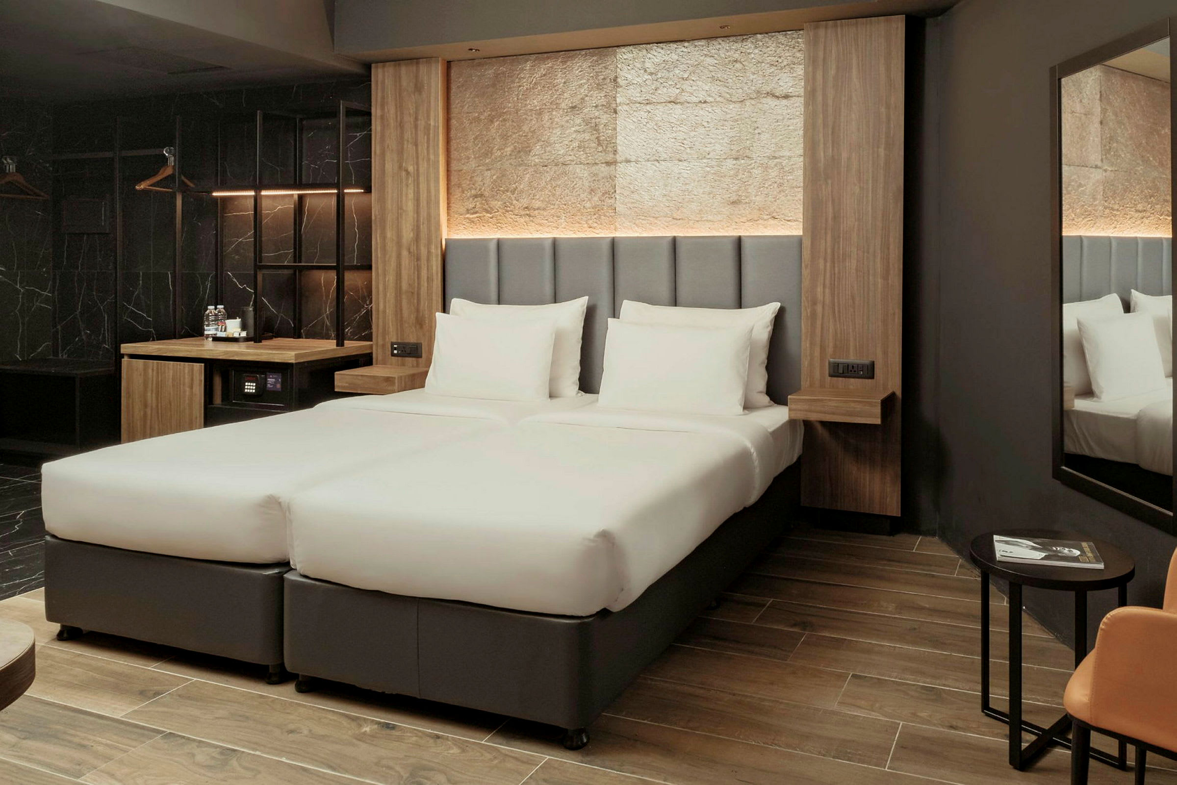 Ett hotellrum med två sammanfogade enkelsängar, en modern inredning och en spegel på väggen. (AI-genererad text)