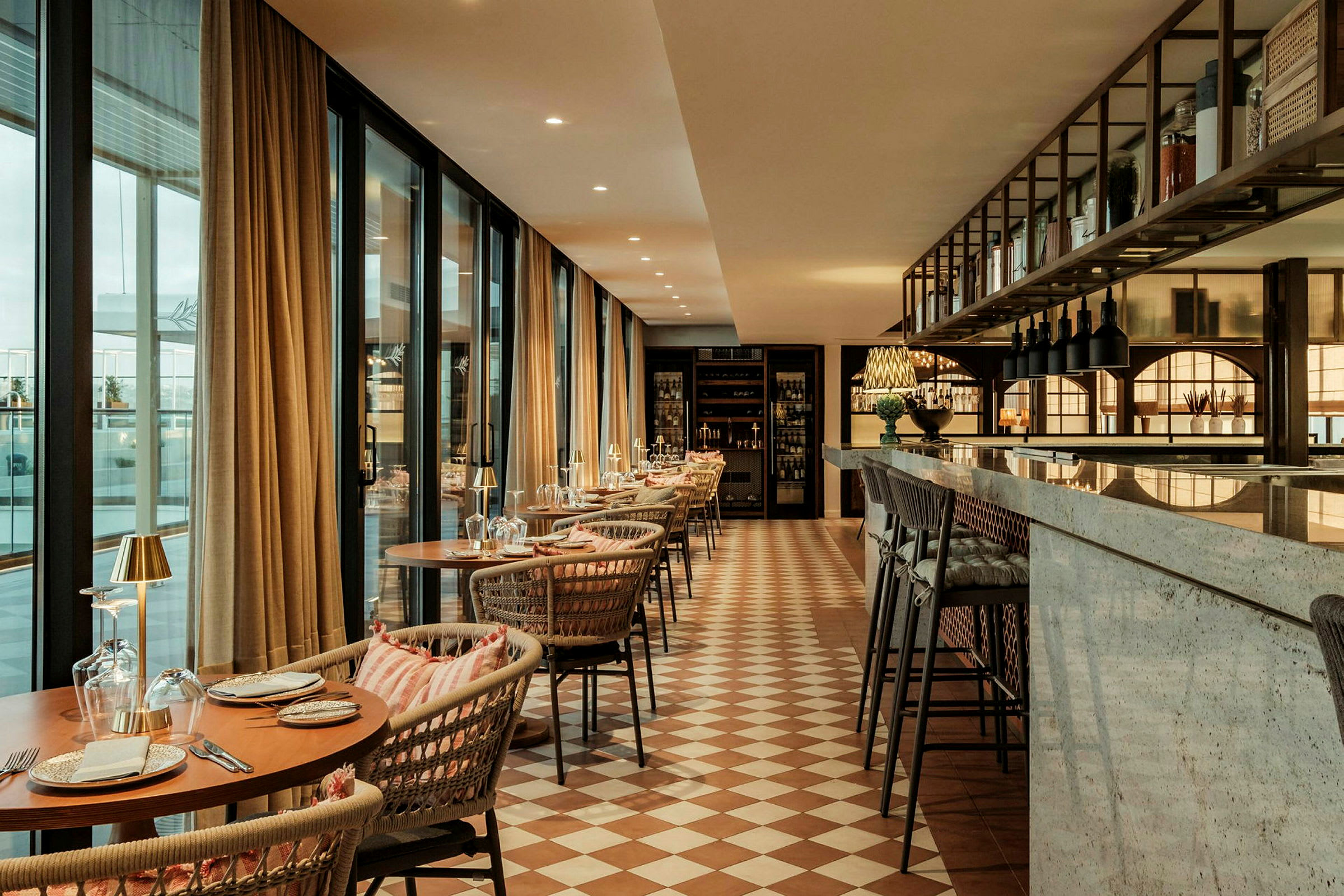En elegant inredd restaurang med dukade bord, mjuka stolar, stora fönster och en marmordisk. (AI-genererad text)