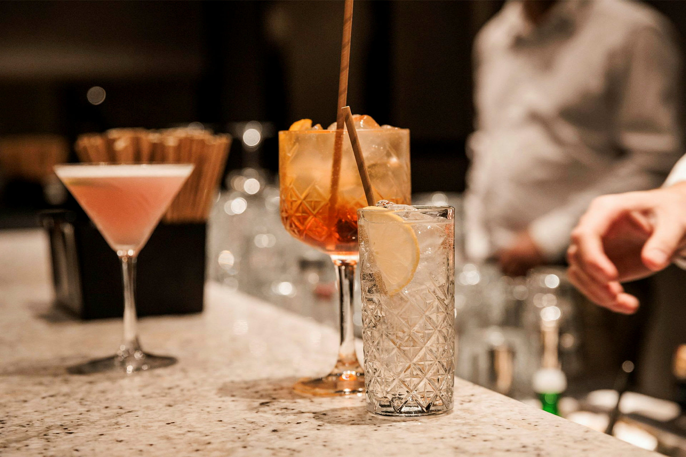 Ett antal glas med olika cocktails står på en marmorbardisk. (AI-genererad text)