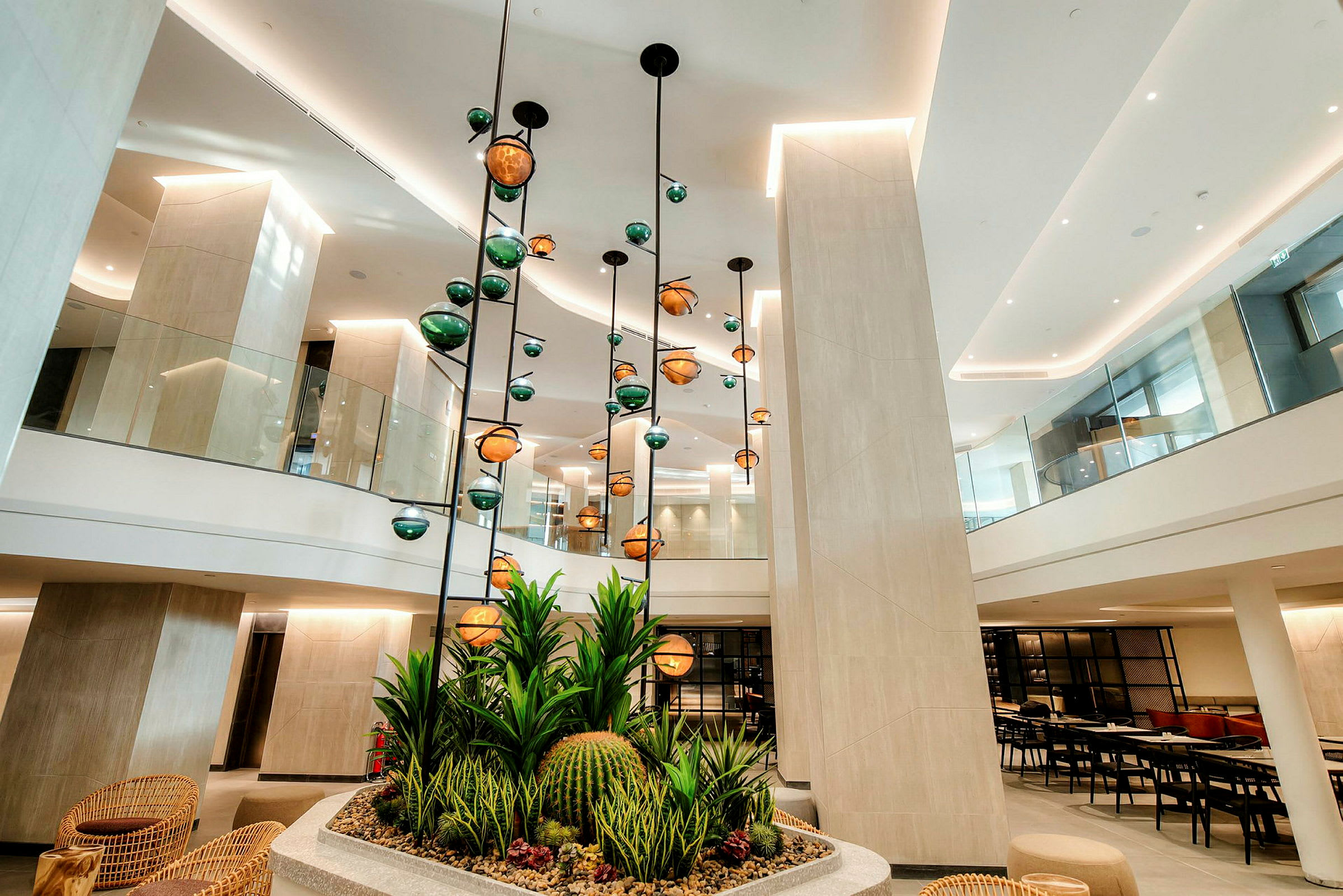 Bild av en modern hotellobby med hängande lampor och dekorativa växter i förgrunden. (AI-genererad text)