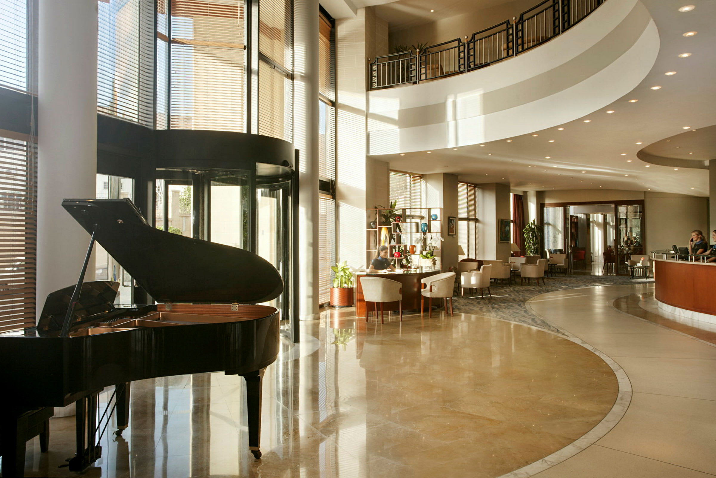 Hotellobby med en flygel, sittgrupper och en reception i bakgrunden. (AI-genererad text)