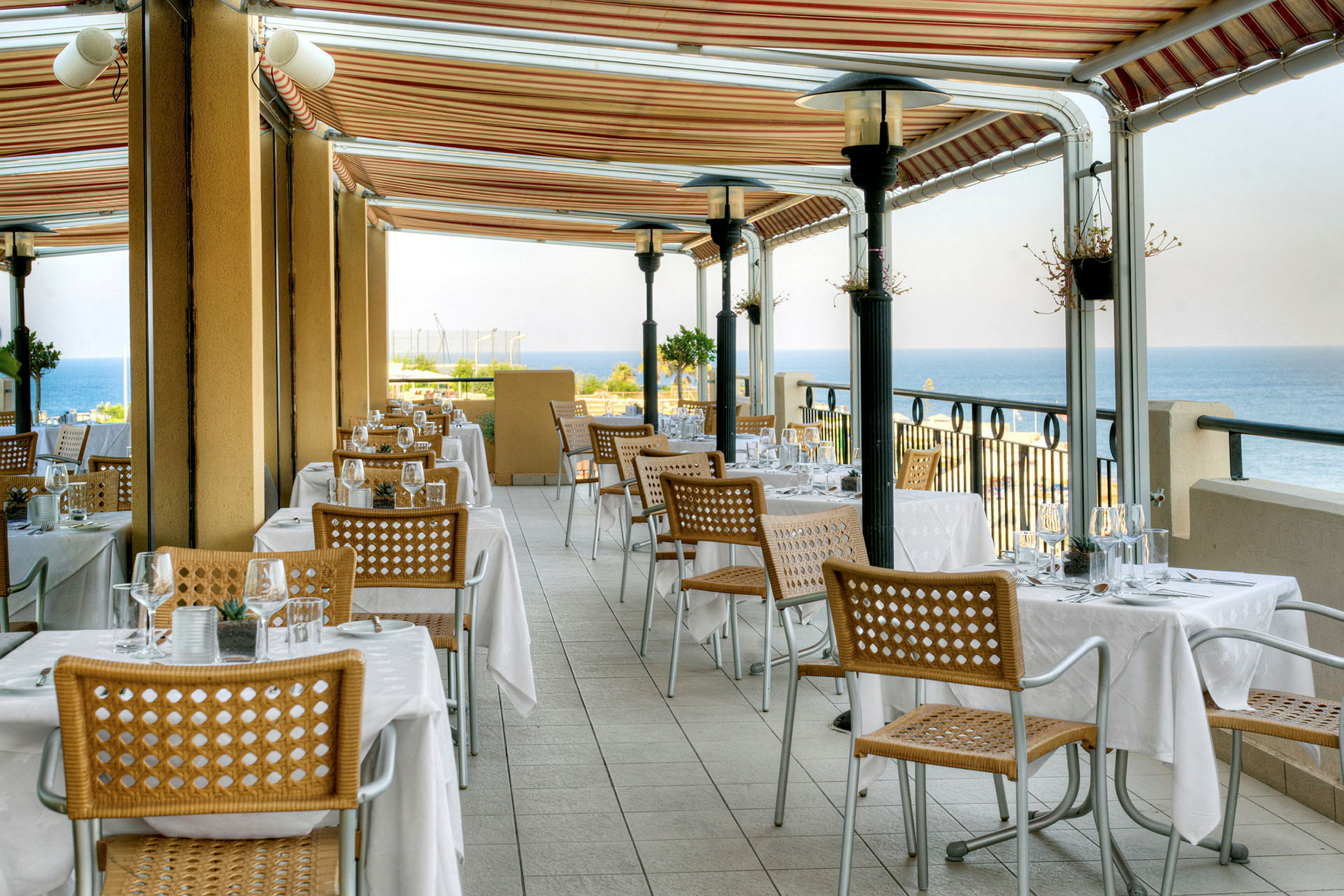 En restaurangterrass med dukade bord och utsikt över havet. (AI-genererad text)