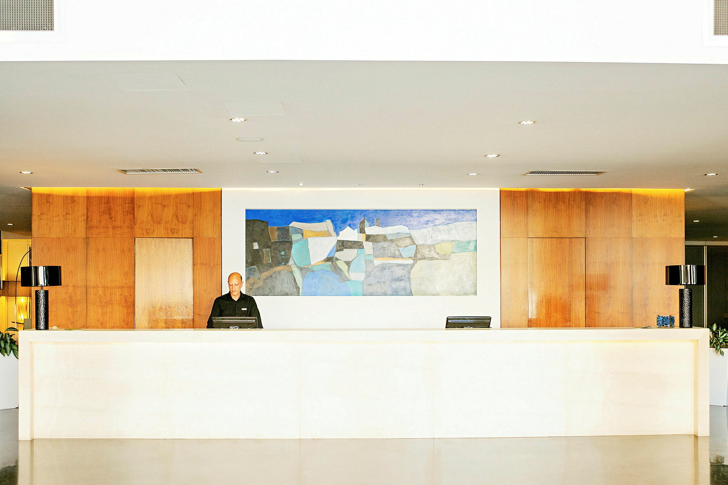 Receptionen i en modern byggnad med en stor abstrakt målning på väggen och trämaterial i interiören. (AI-genererad text)