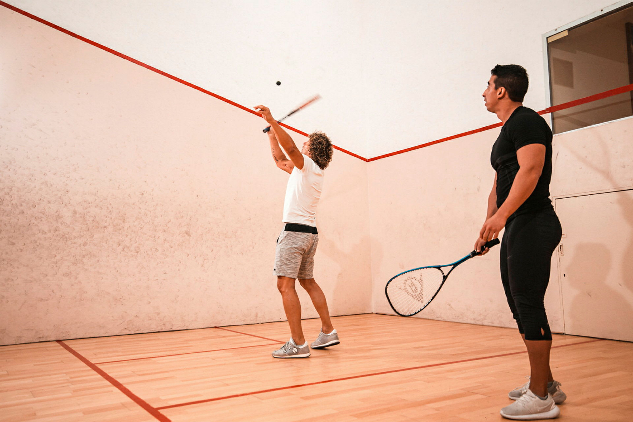 Personer spelar squash på en inomhusbana. (AI-genererad text)