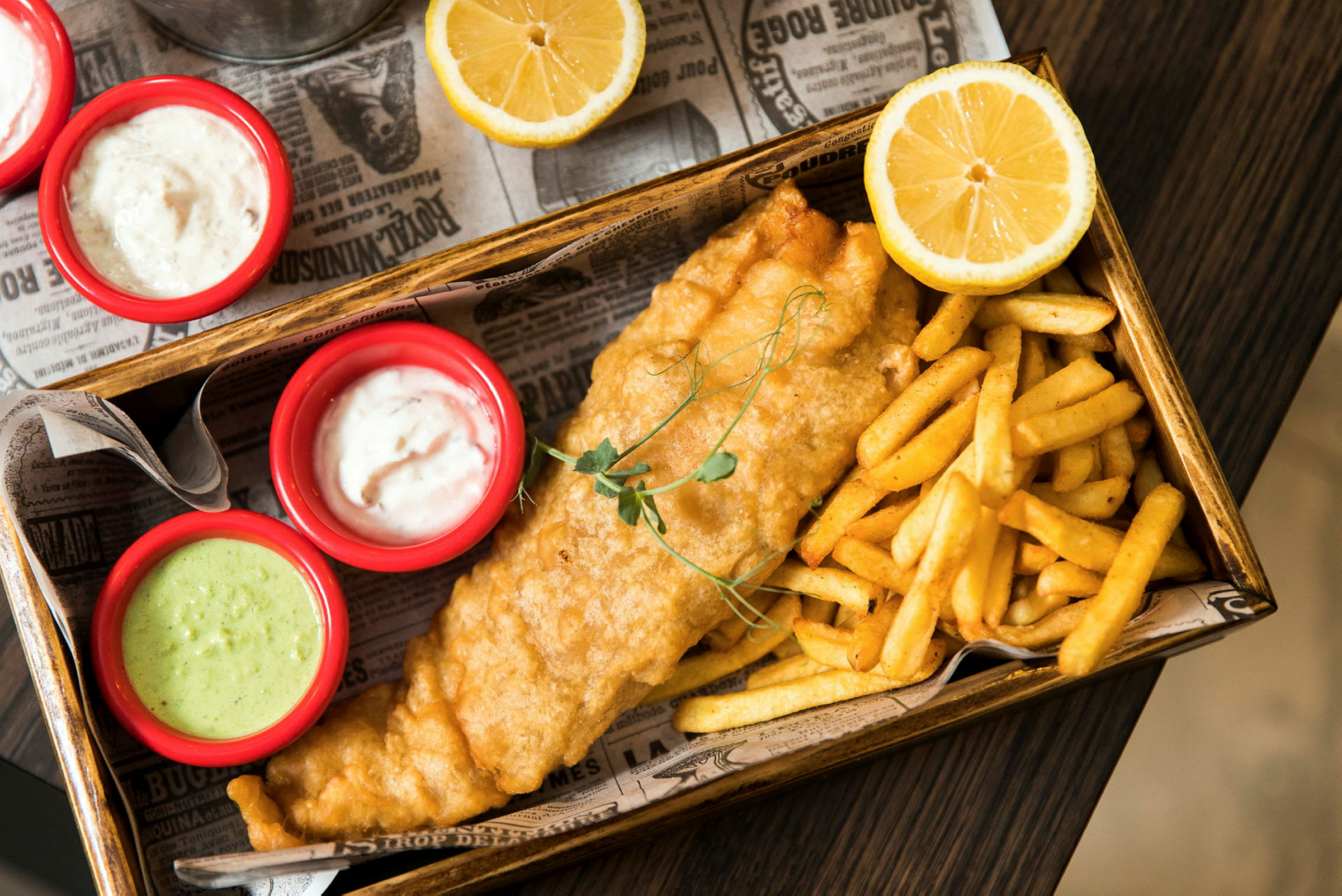 Fish and chips serverad med såser och citronhalvor. (AI-genererad text)
