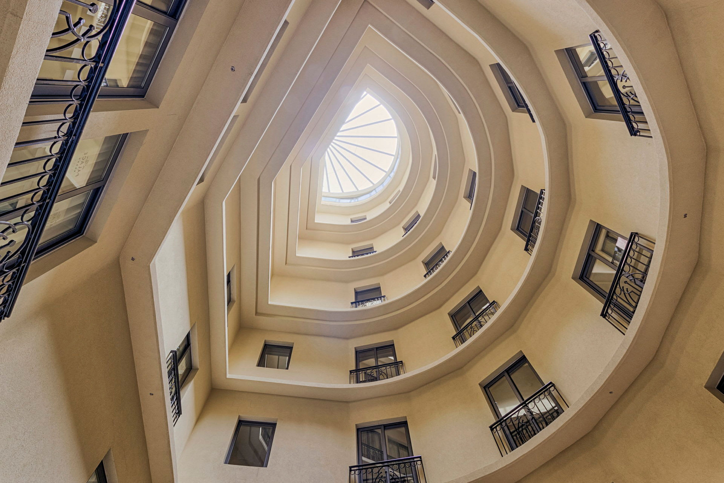Bild på en byggnads interiöra atrium med flera våningar och fönster som omger ett öppet, geometriskt tak. (AI-genererad text)